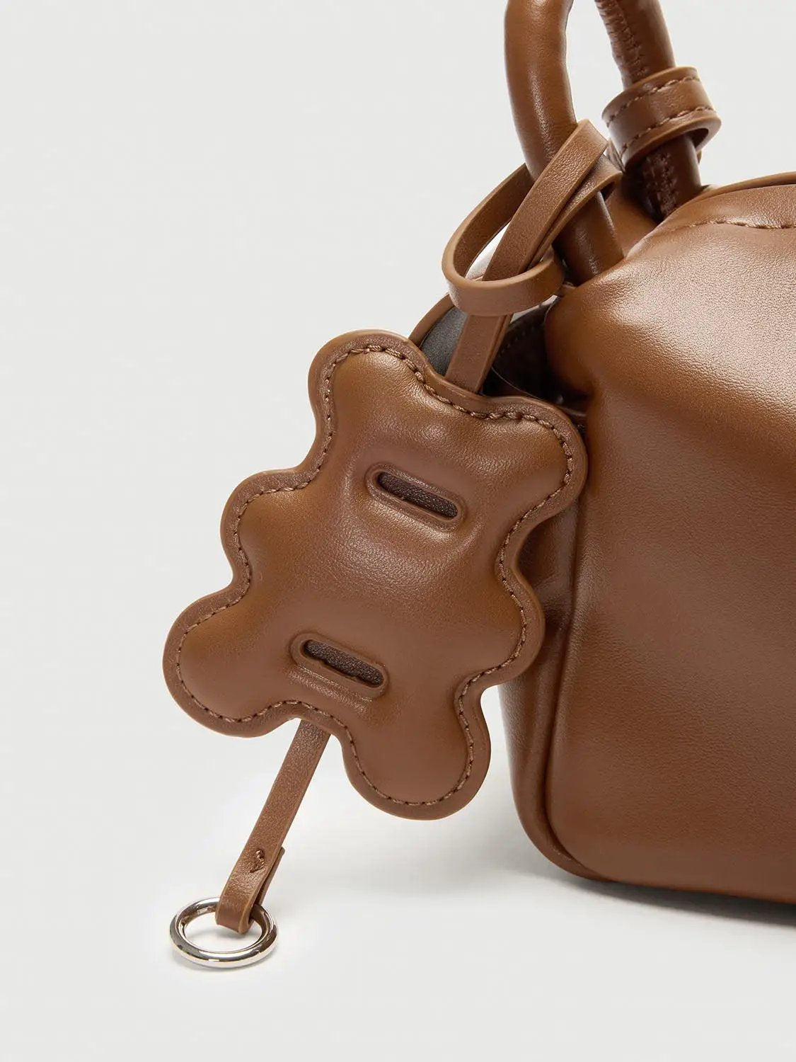 Top Handle & Crossbody Bag in tan brown leather with a flower-shaped charm and metal ring