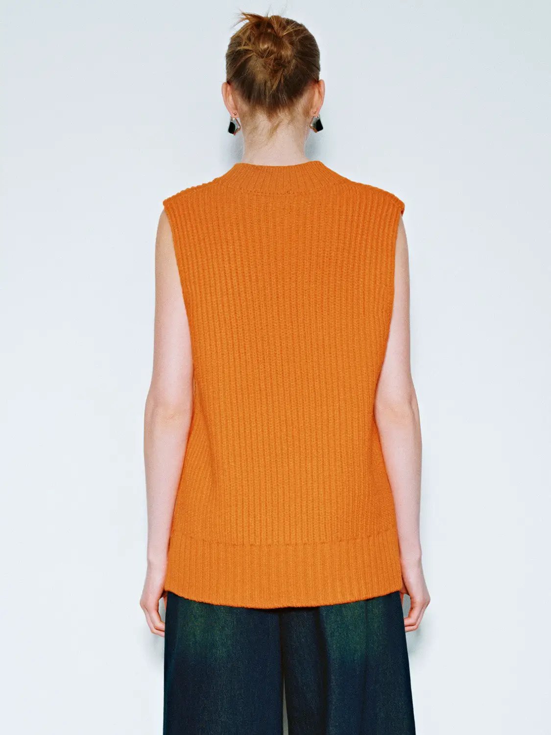Loose V-Neck Knitted Vest in orange; sleeveless, ribbed knit, back view on model.