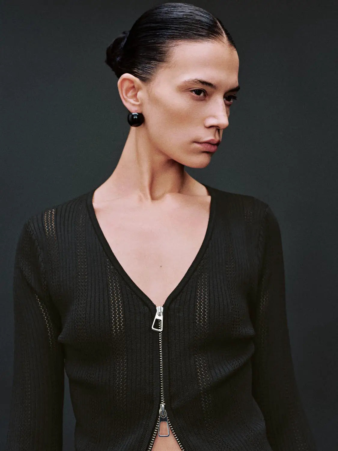 Zip-up front black knitted cardigan worn by model; V-neck, long-sleeve design.