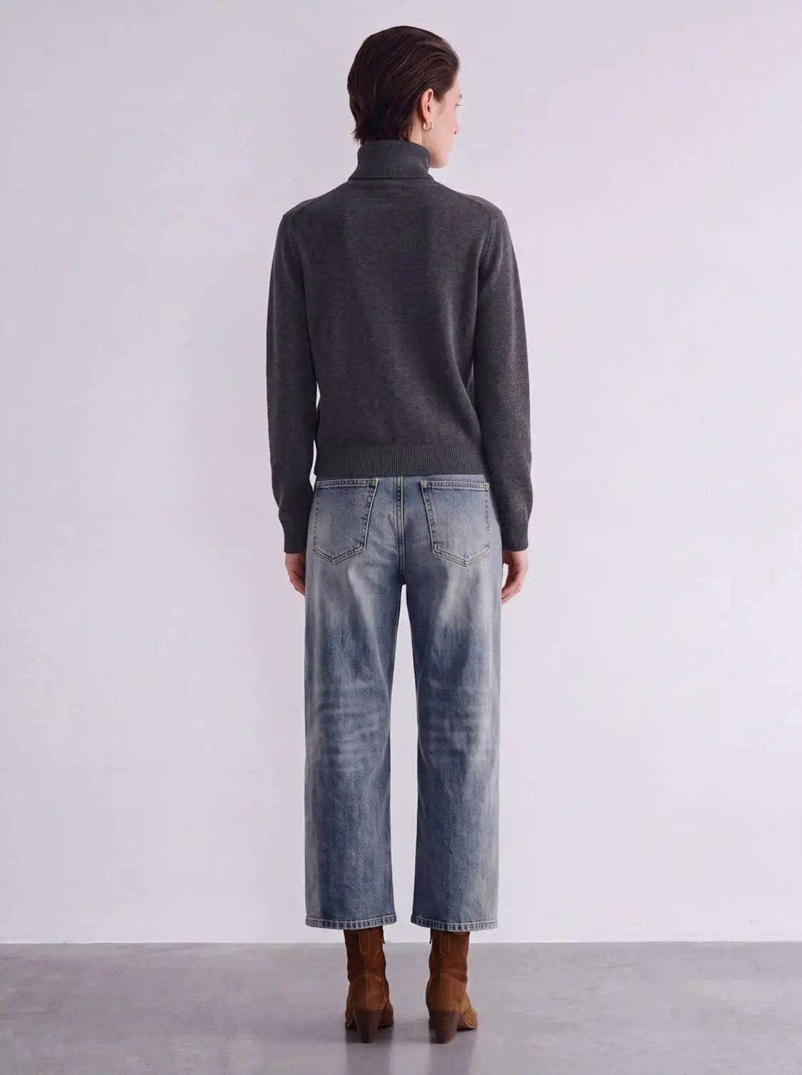 Mock neck knitted cardigan in charcoal gray, ribbed hem, back view with light-wash jeans.