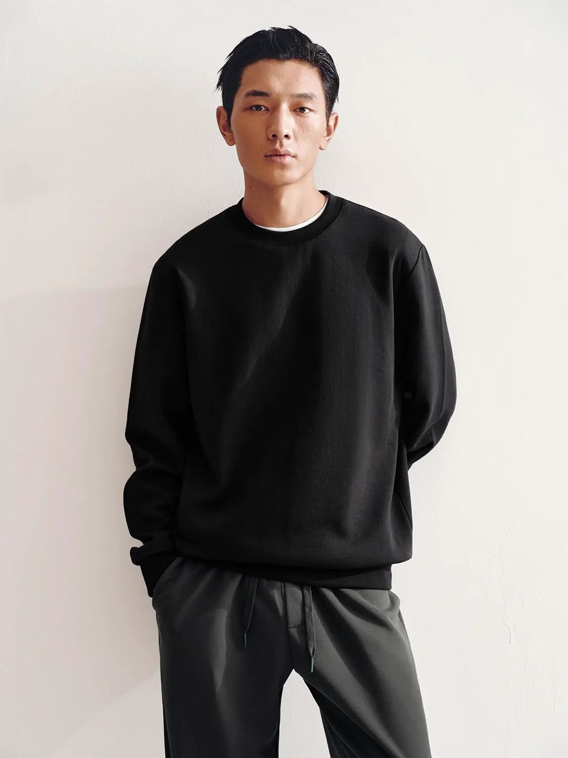 Sweatshirt in black worn by male model; relaxed-fit crewneck.