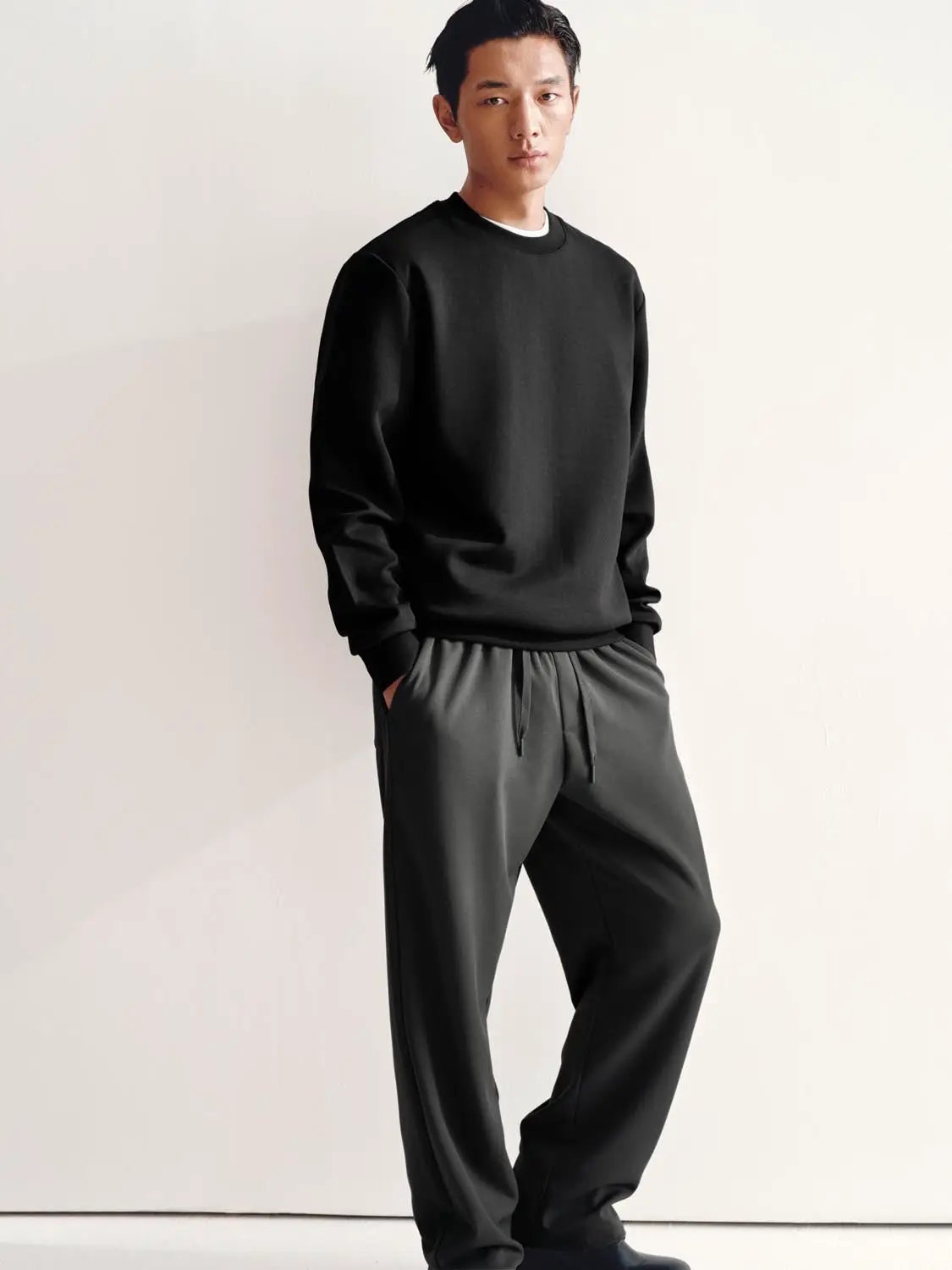 Sweatshirt black crew-neck on male model wearing gray jogger pants for a minimalist look