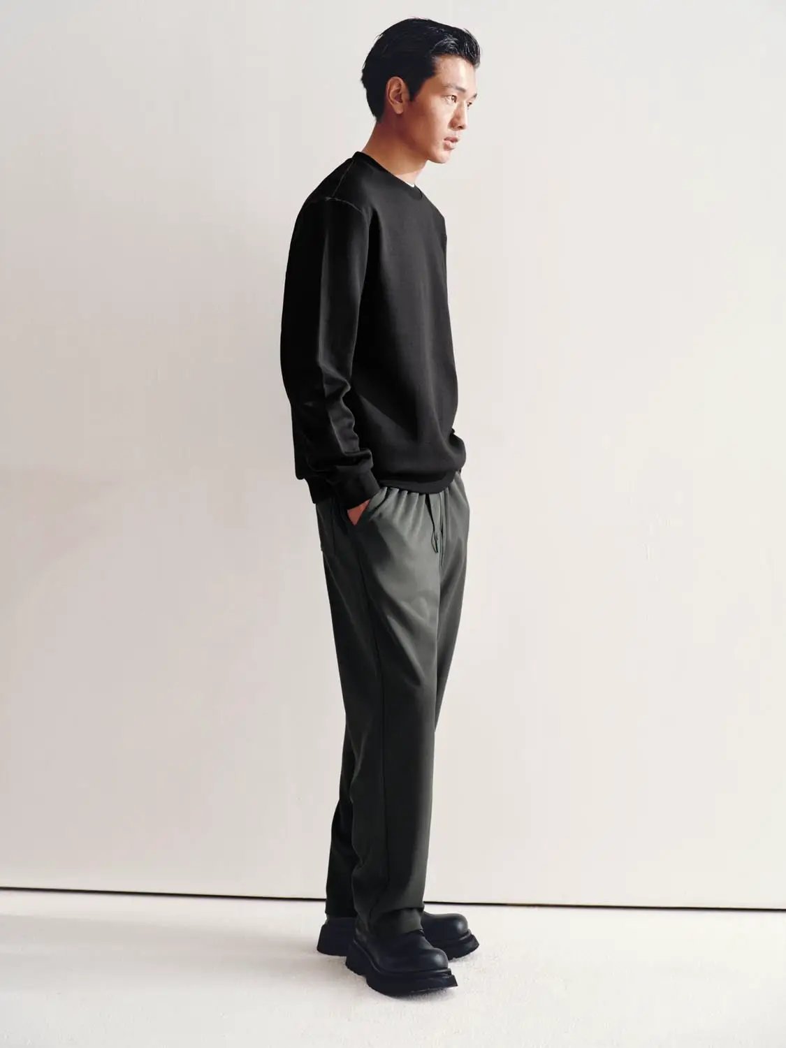 Sweatshirt in black with gray jogger pants, worn by a male model