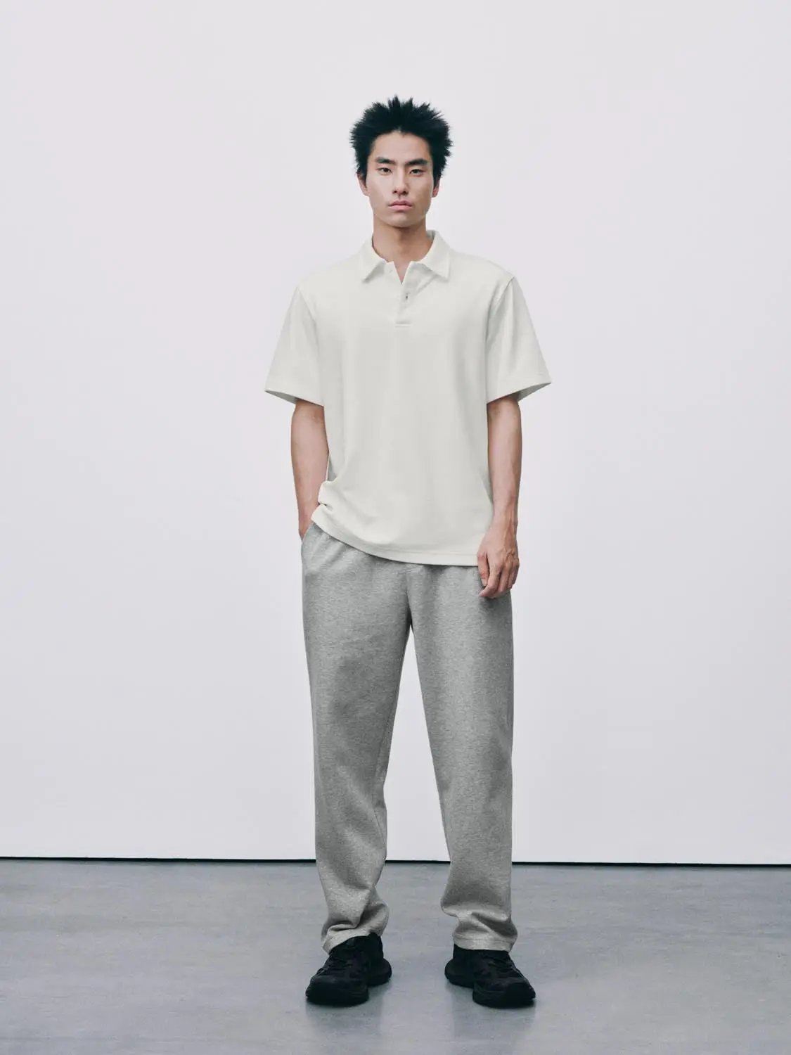 Textured Brushed Polo Cotton Blend Shirt; cream short-sleeve polo worn by male model, paired with grey sweatpants
