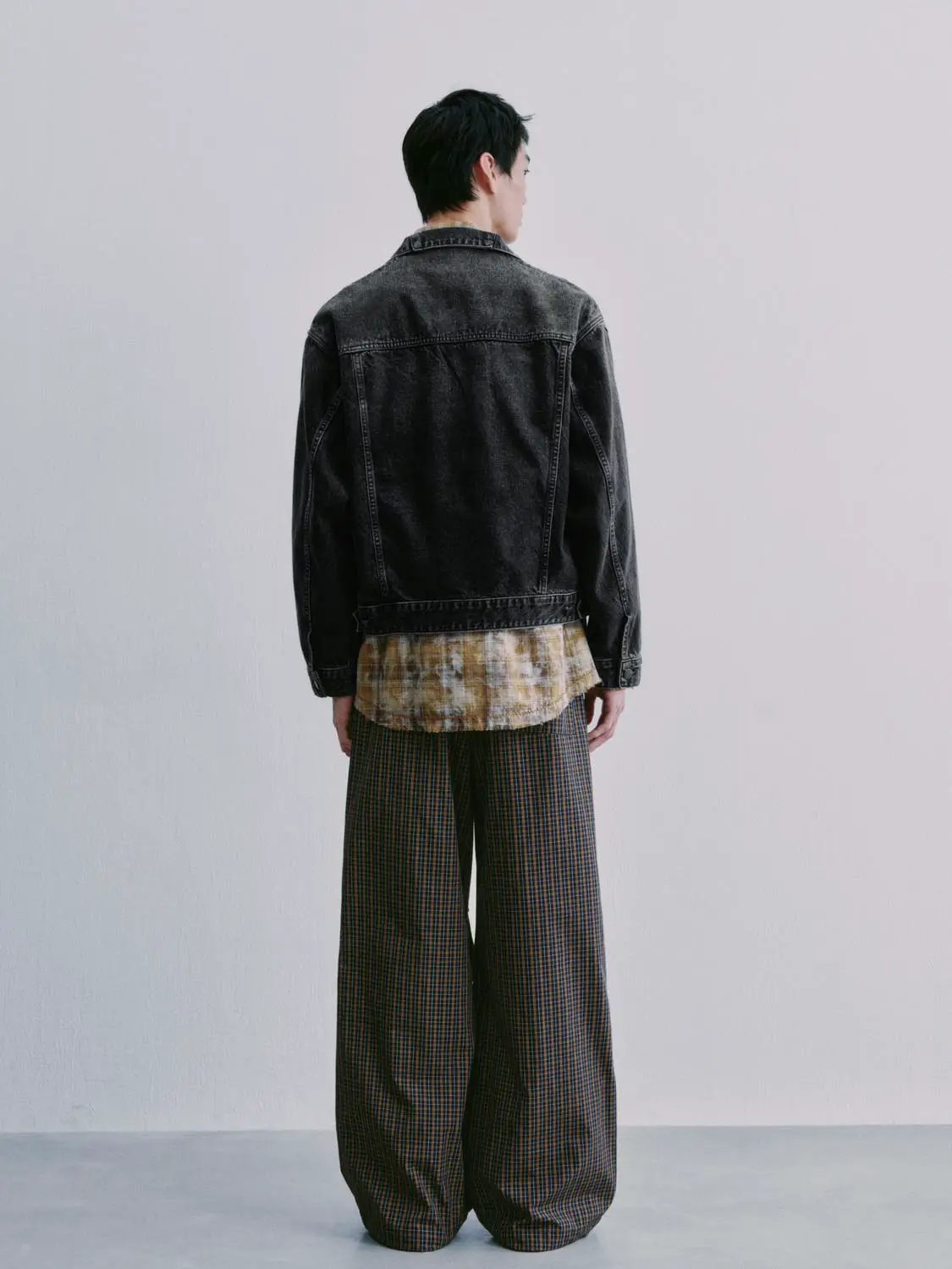 Denim jacket, dark wash, back view on model with layered tan shirt and plaid pants