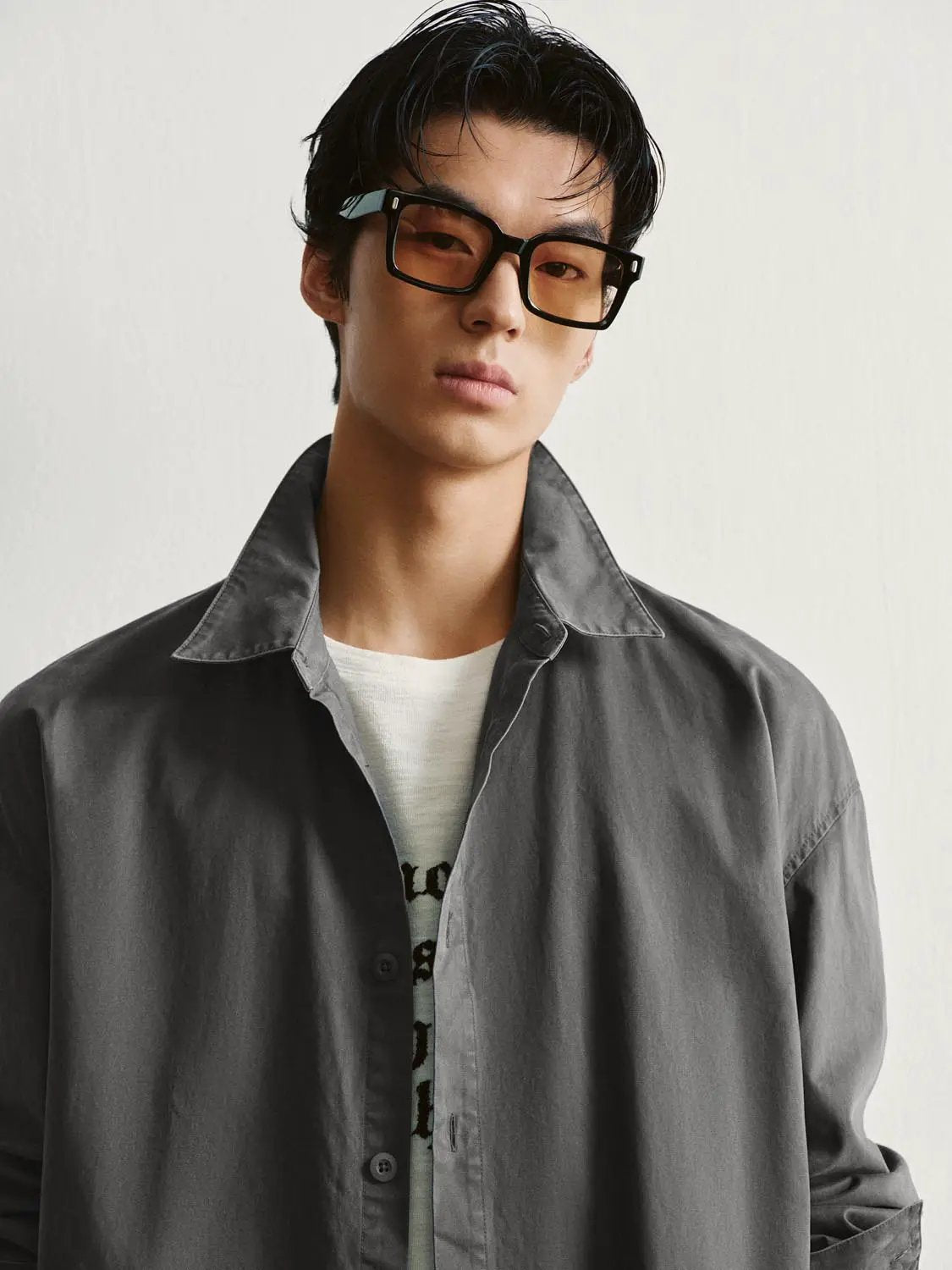 Button-front gray shirt worn by a model, layered over a light tee.