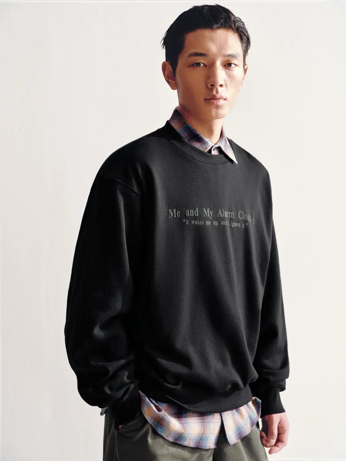 Sweatshirt by Urban Revivo Fashion in black with chest graphic; layered over a plaid shirt.