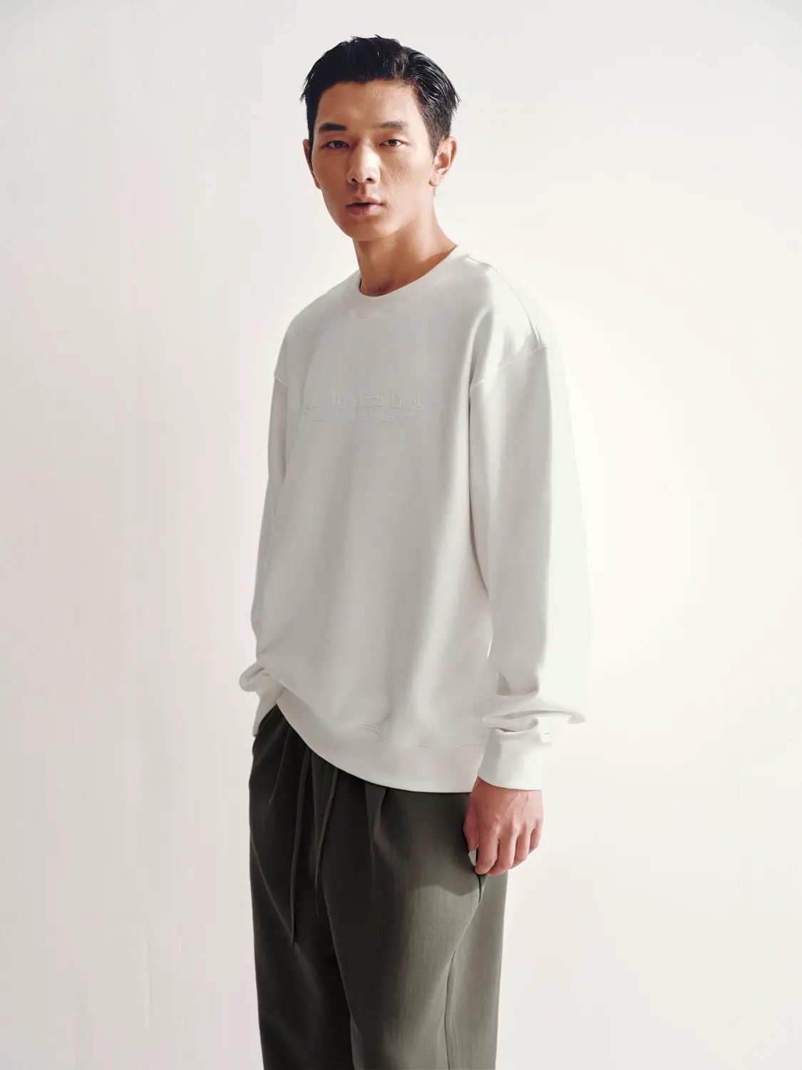 Sweatshirt white oversized crewneck on male model; minimal design