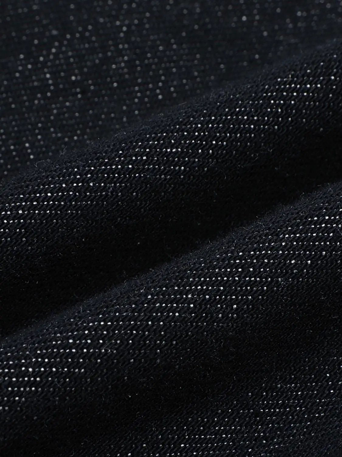 Jeans fabric close-up in dark indigo denim with a textured weave.