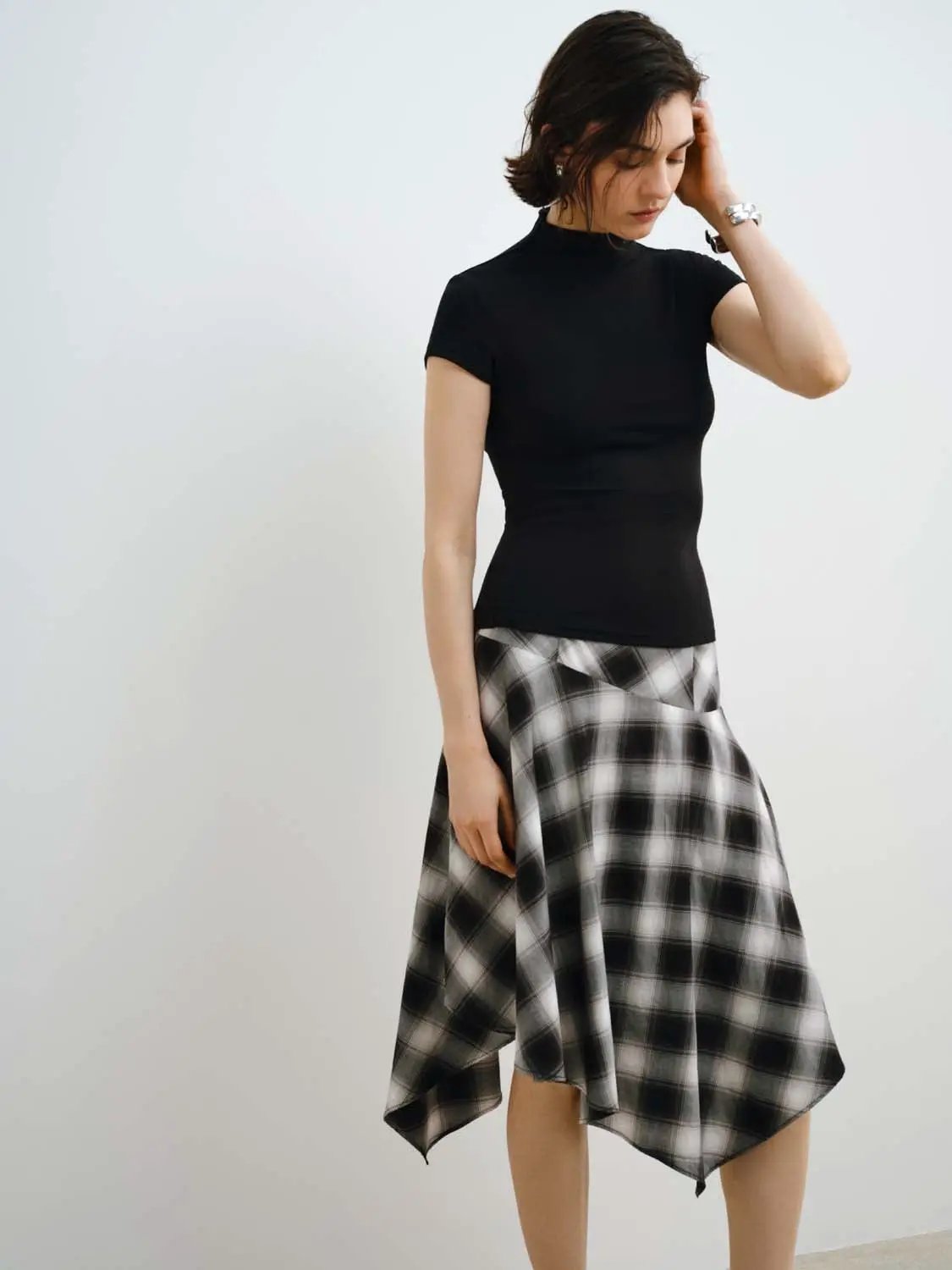 Womens black modal-knit T-shirt with high neck, paired with a black-and-white plaid skirt (two-piece outfit).