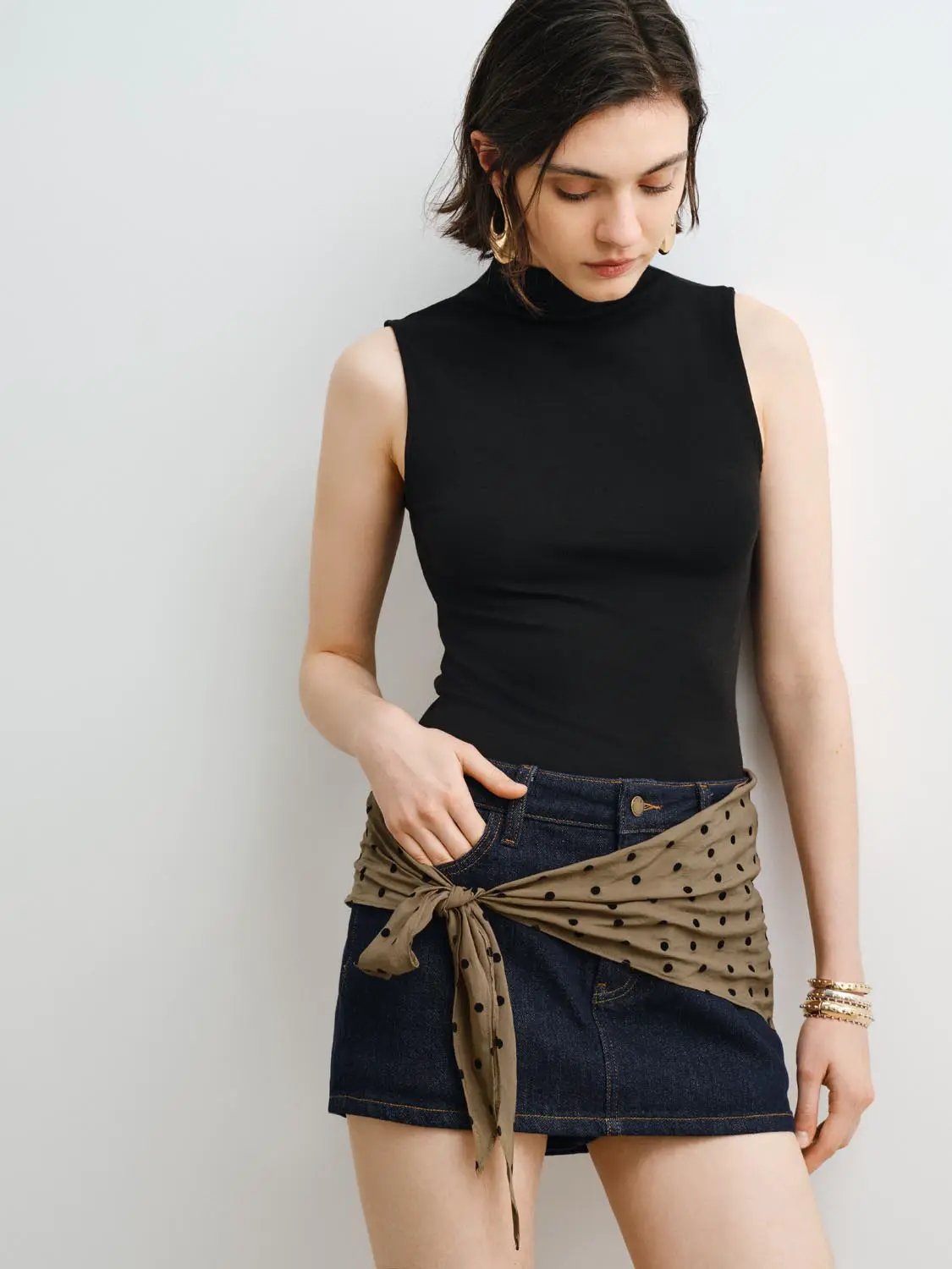 Tank Top, black sleeveless high-neck, paired with denim shorts and beige polka-dot scarf.