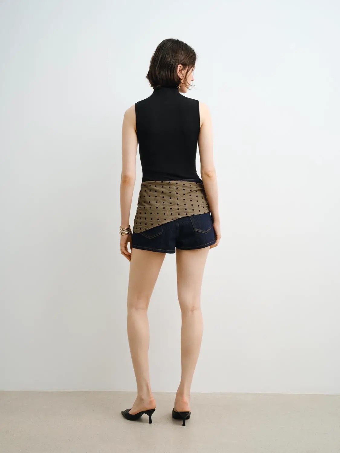 Tank Top; black sleeveless top with beige polka-dot wrap over denim shorts (back view)