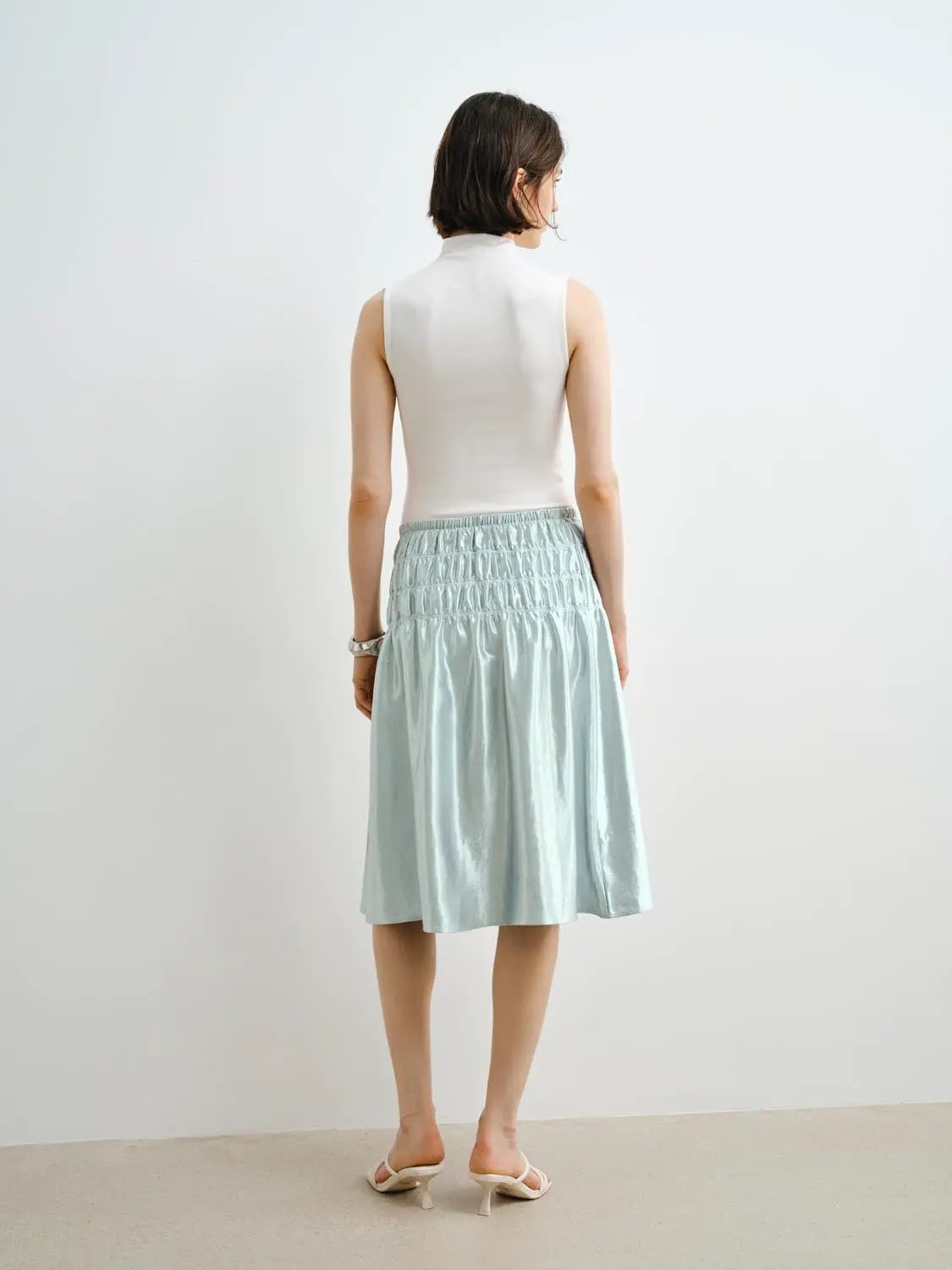 Tank top, white sleeveless, paired with light blue smocked-waist skirt; back view on model.