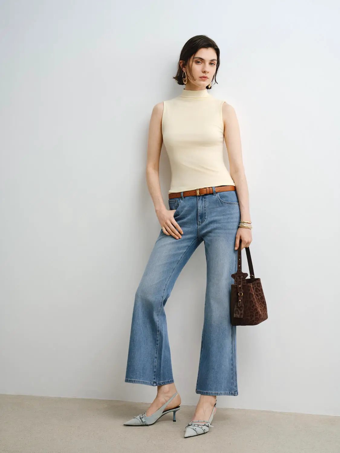 Tank Top in beige, sleeveless mock-neck style worn with blue denim jeans and brown belt.