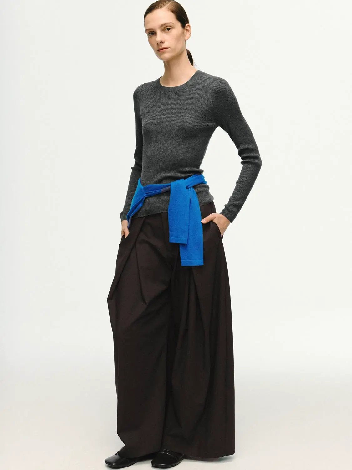 Ribbed gray fitted long-sleeve crew-neck knitted T-shirt with a blue belt over dark wide-leg pants