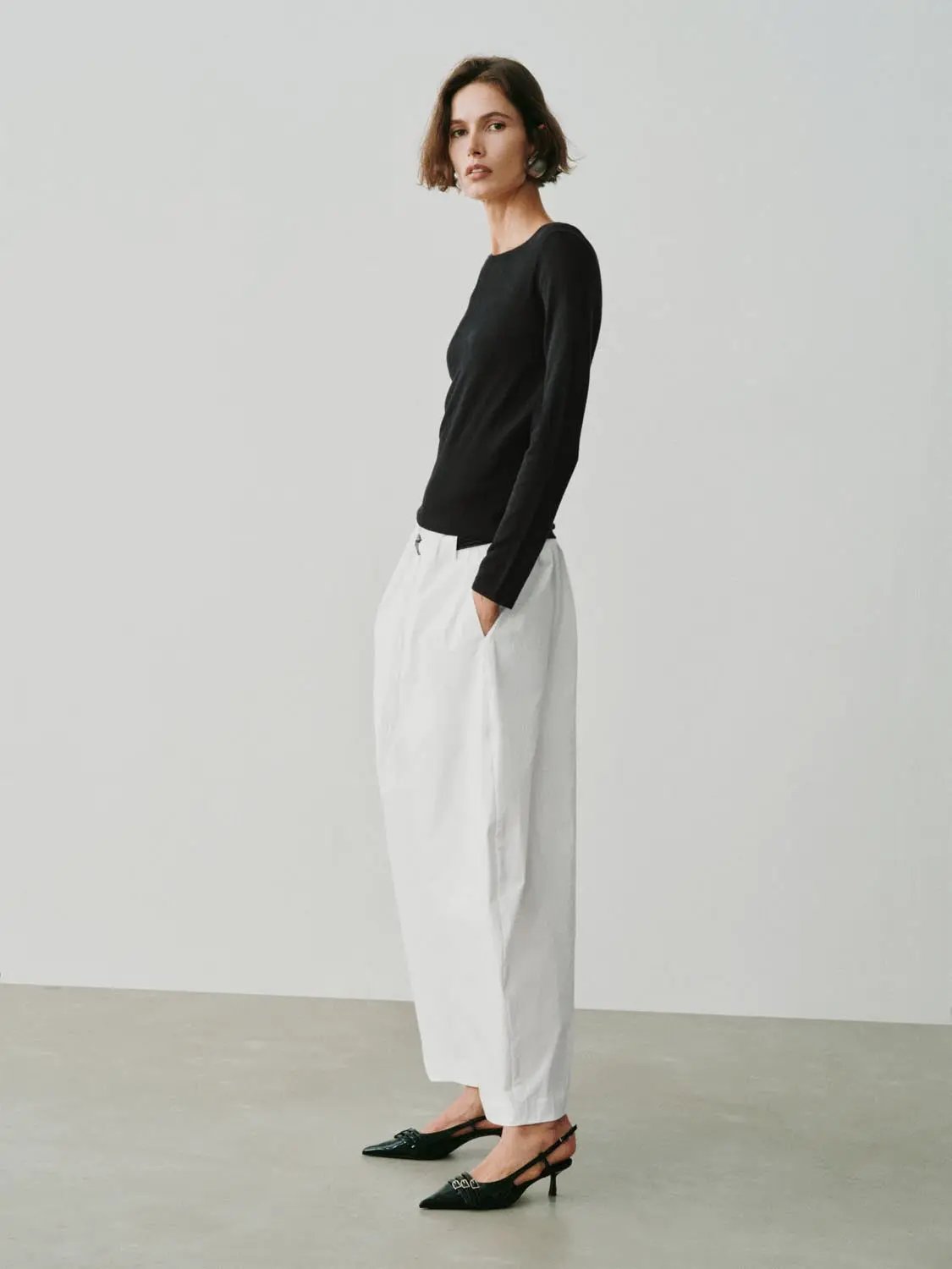 Knit T-Shirt in black, long-sleeve knit top worn by model with white wide-leg pants