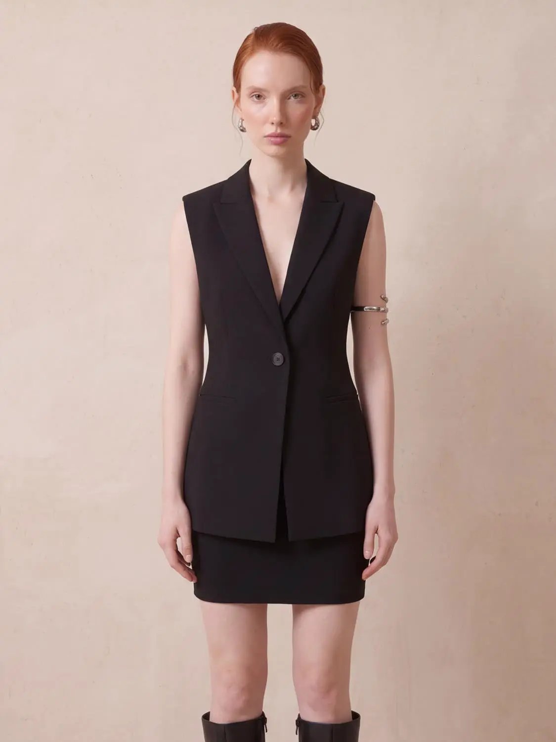 Sleeveless black single-button vest, blazer-style, worn by model.
