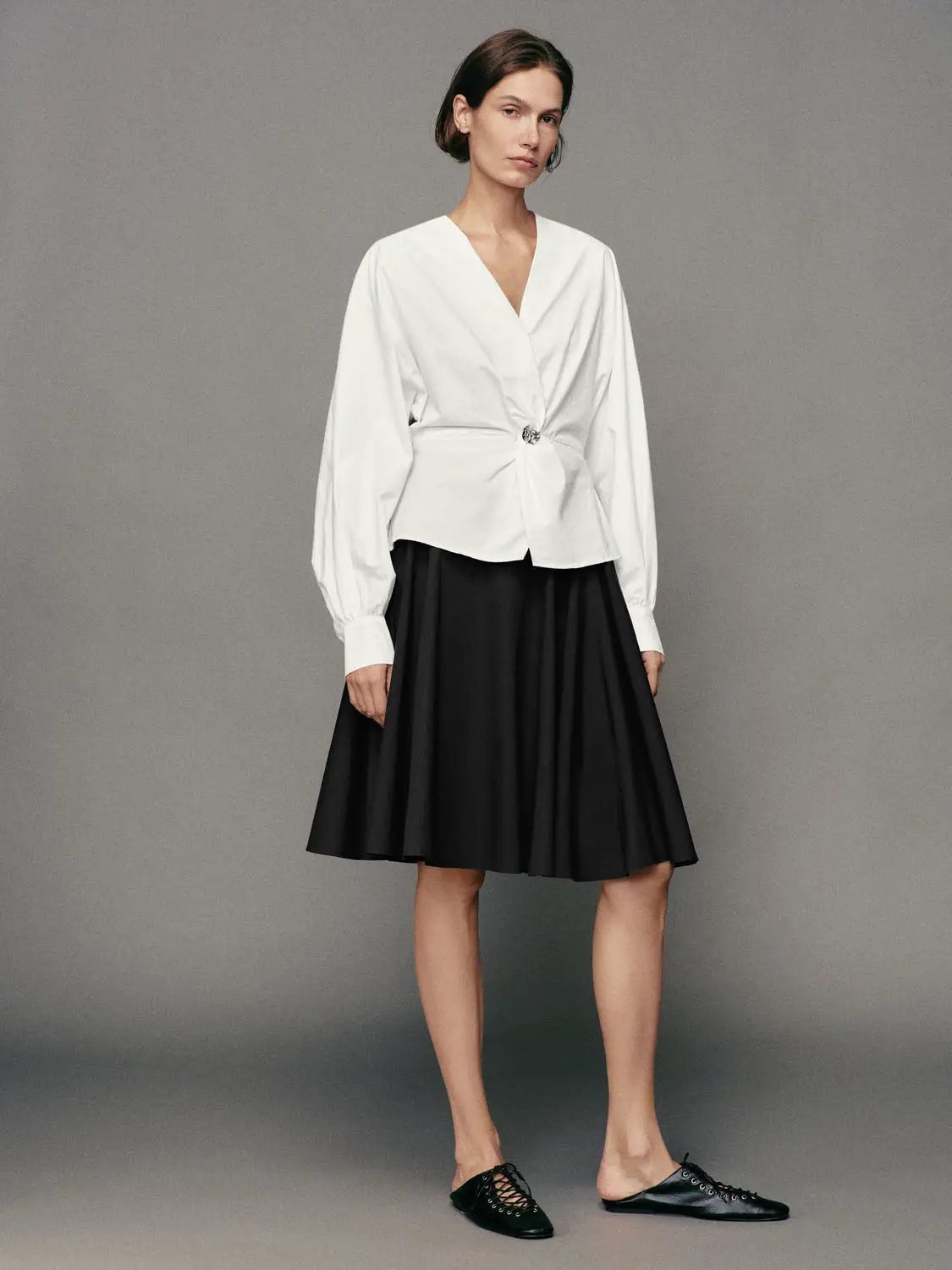 Pleated high-waisted cotton A-line skirt in black, versatile wardrobe staple.
