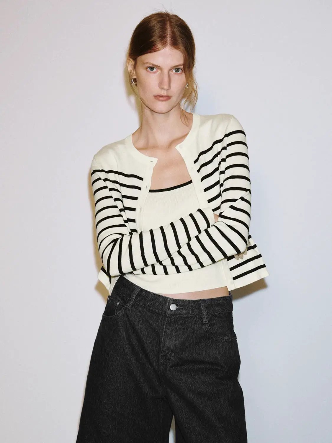 Knit cardigan in cream with black striped sleeves, cropped length, worn over a white top.