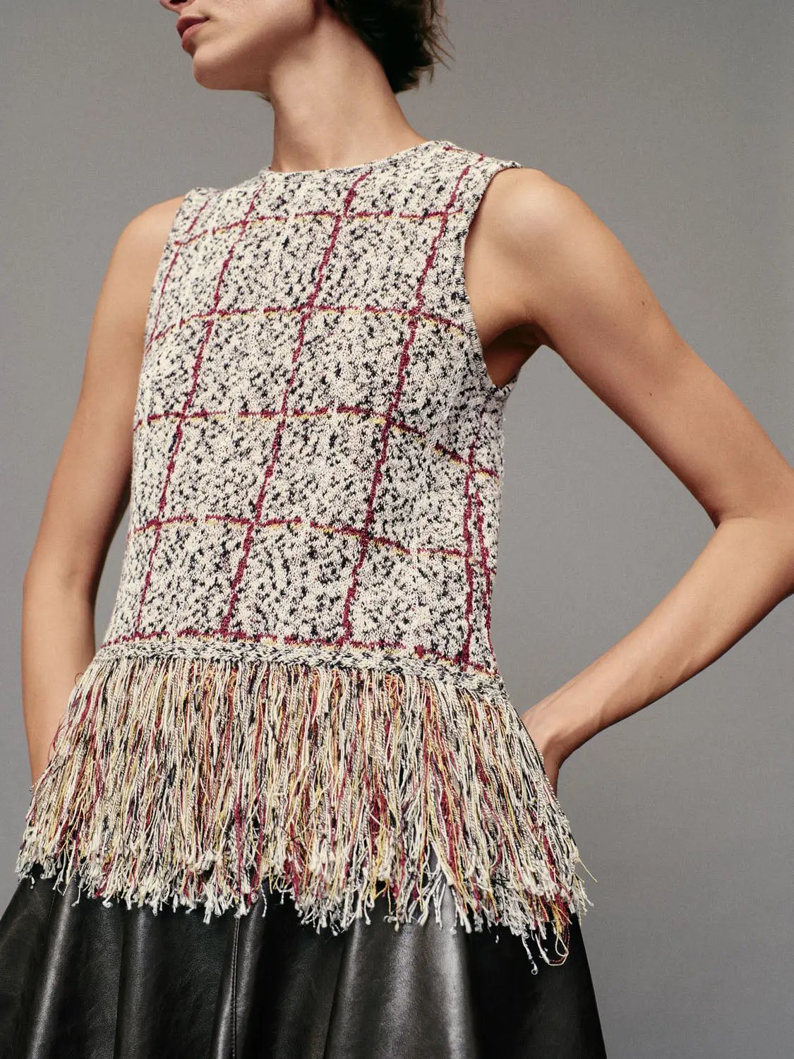 Checked fringe-hem sleeveless knit top with crew neck in cream plaid accented with red and black lines.
