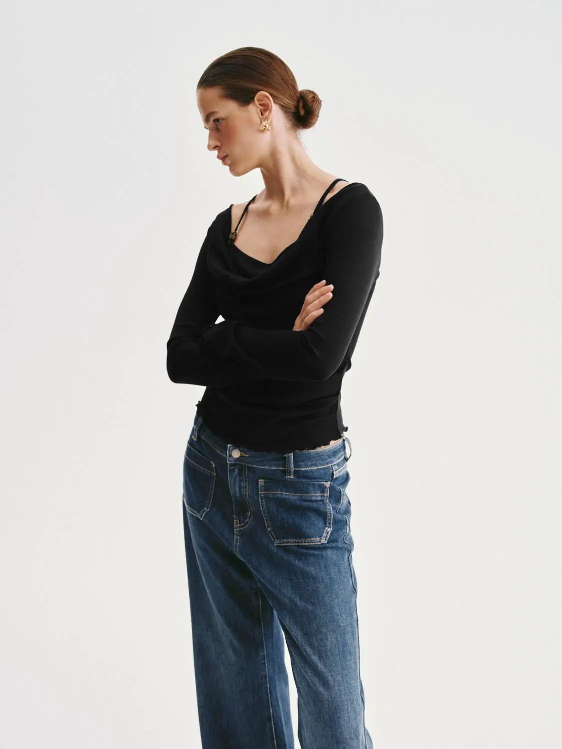 Black long-sleeve T-shirt with a draped neckline, paired with blue jeans.