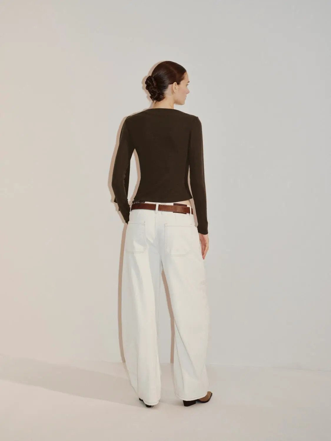 Draped One-Shoulder Long Sleeve Blouse; black knit top with white wide-leg pants and brown belt