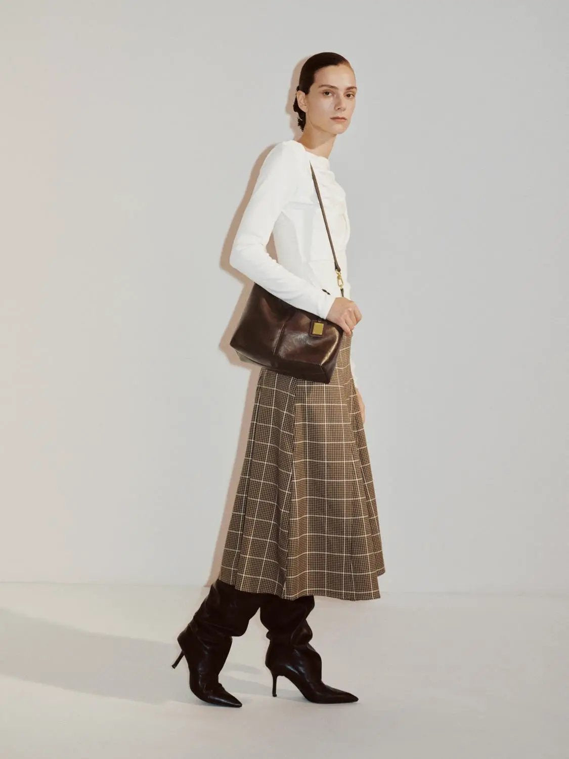 Draped One-Shoulder Long Sleeve Blouse in white worn by model with brown plaid skirt and handbag