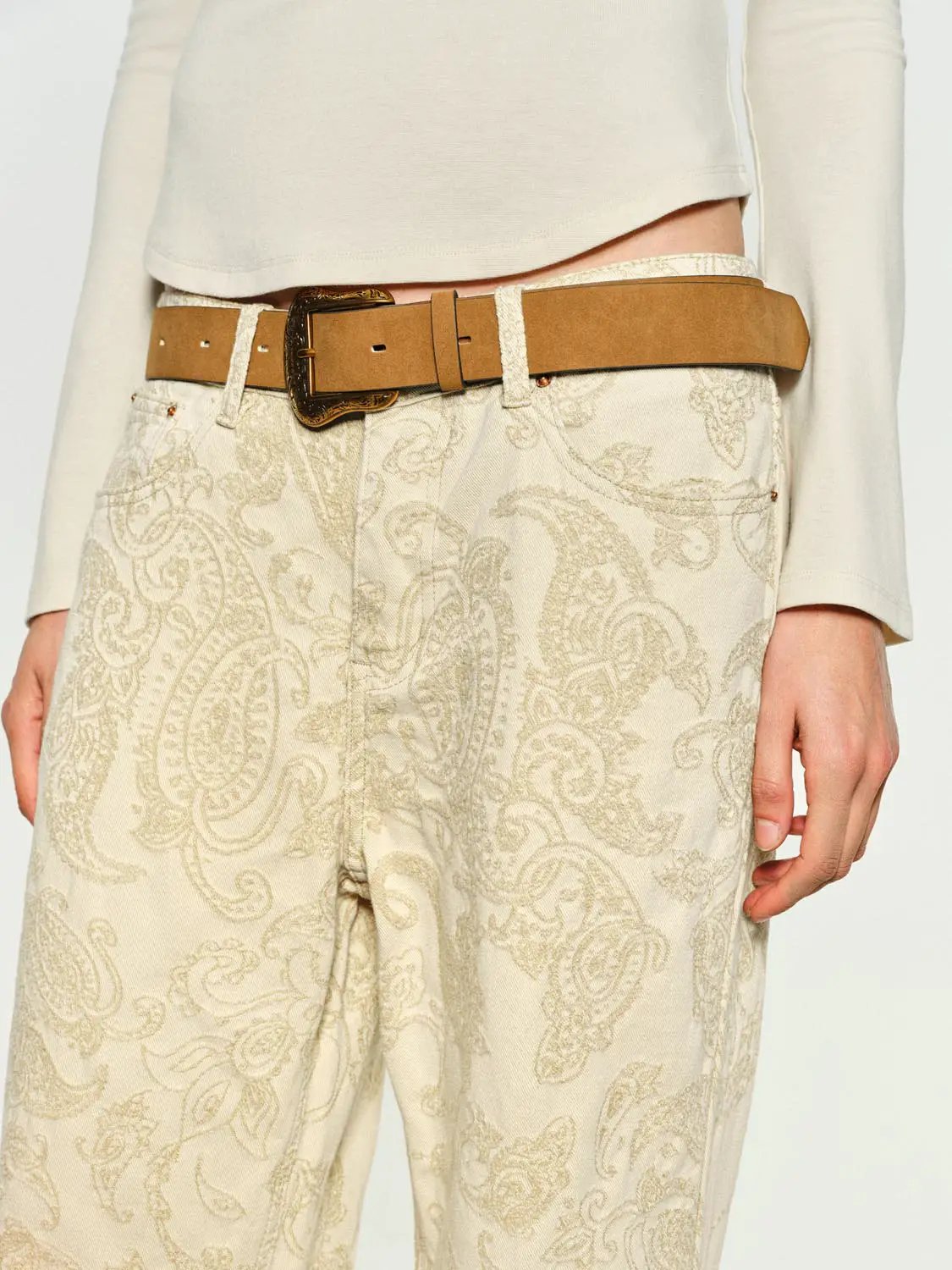 Jeans with cream paisley print, wide-leg fit, paired with tan leather belt