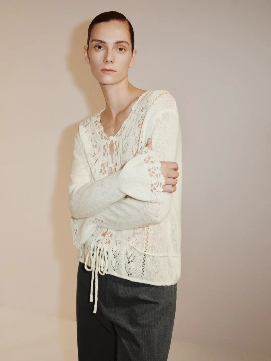 Textured cream knit cardigan with V-neck, lace panels on sleeves, and a tie waist.
