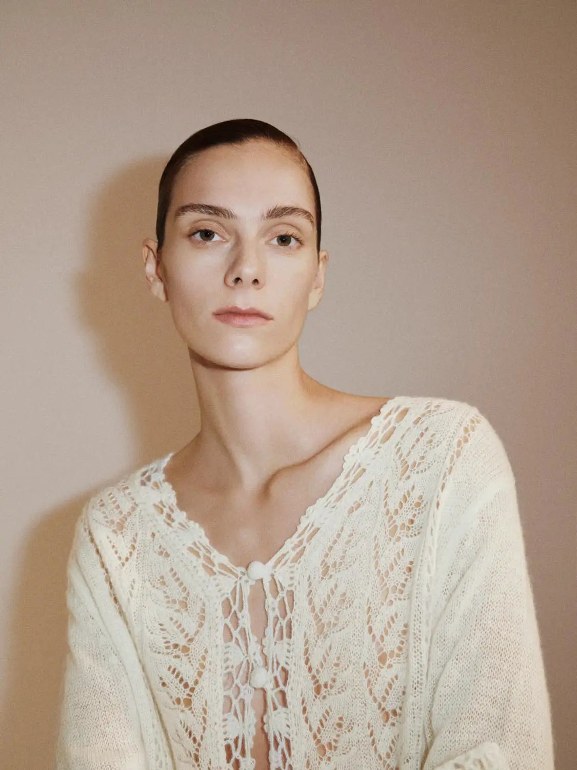 Ivory knitted cardigan with lace texture, V-neck and long sleeves.