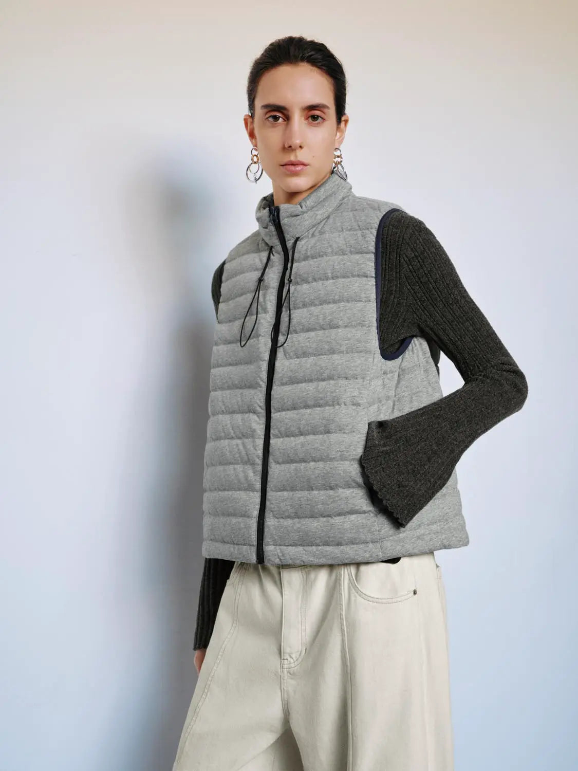 Urban Revivo gray quilted down jacket vest with front zipper, layered over a dark knit sweater
