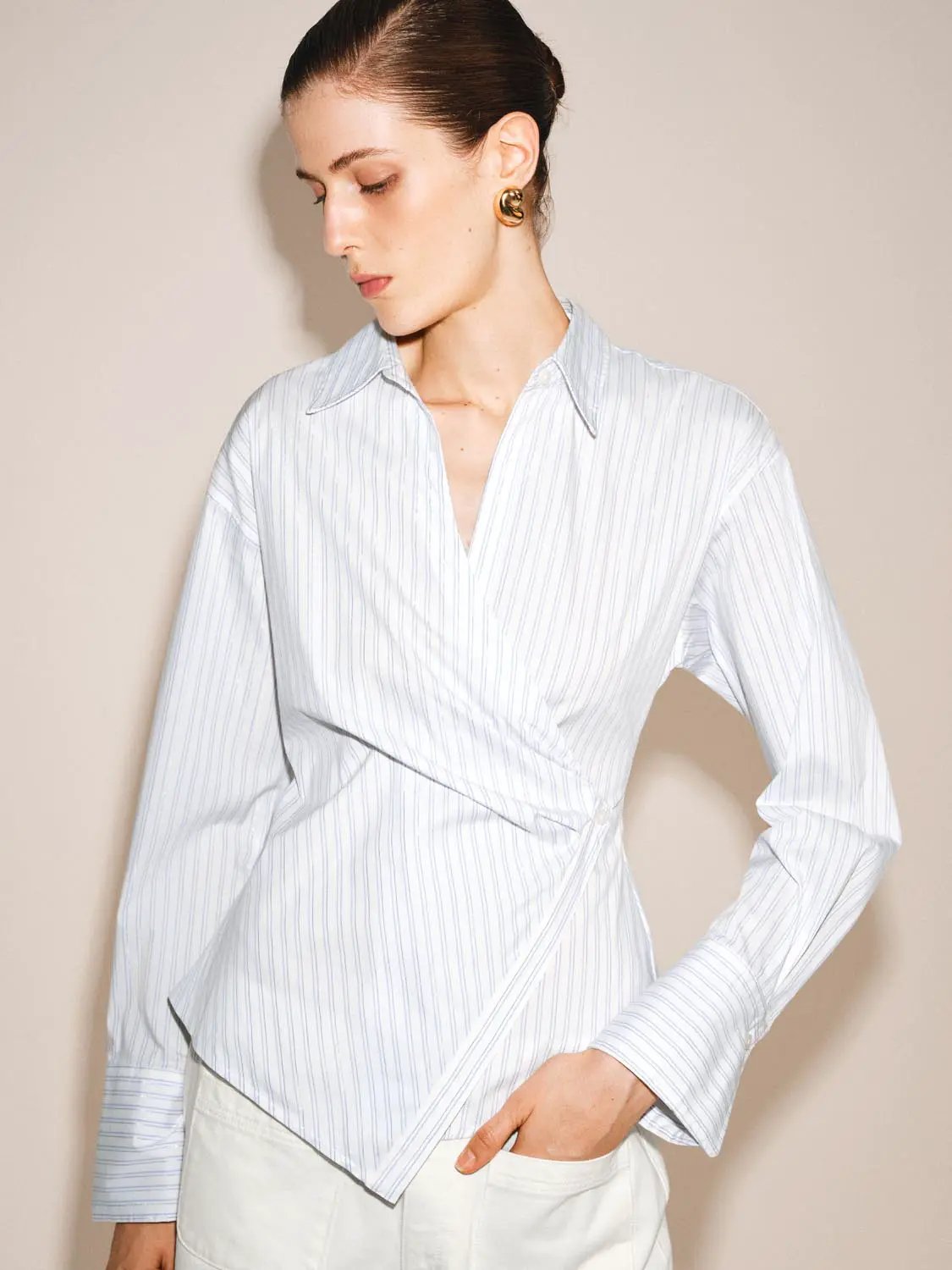 Shirt with wrap-front, white fabric with blue pinstripes, long sleeves, shown on model wearing white pants