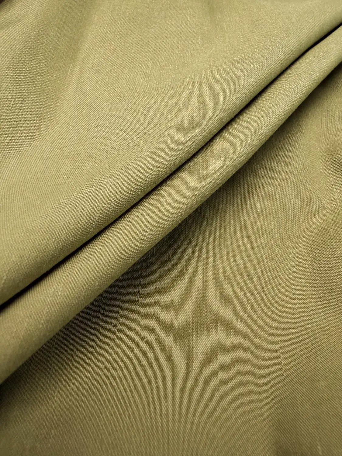 Blouse fabric in olive green with smooth, folded texture.