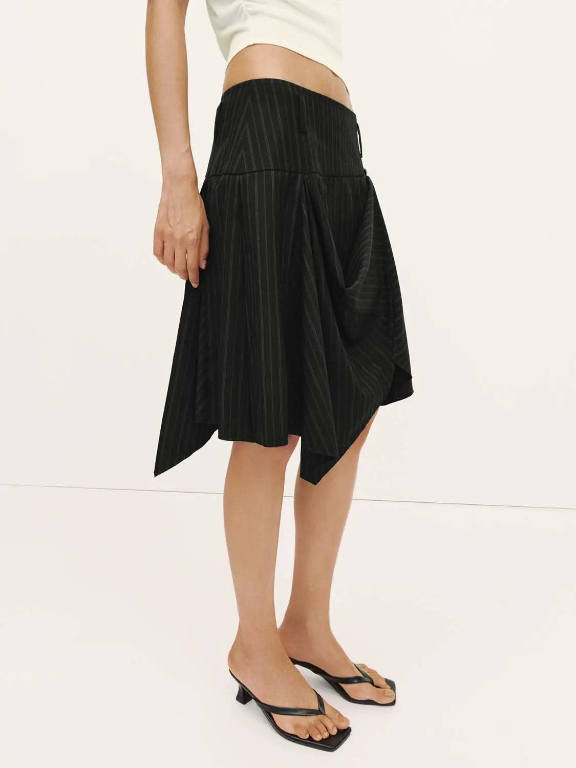Pinstripe high-waist draped wrap midi skirt in black with asymmetric hem