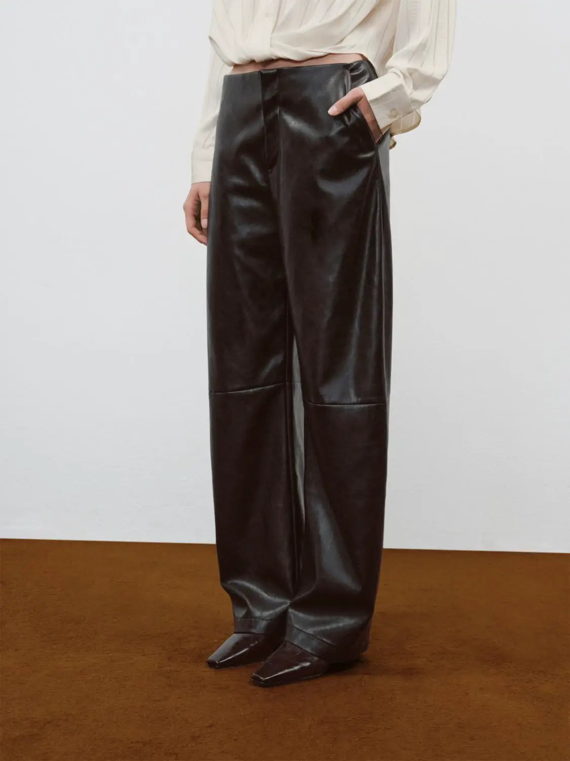 Mid-rise curved-leg faux leather pants in black by Urban Revivo Fashion; barrel-leg style
