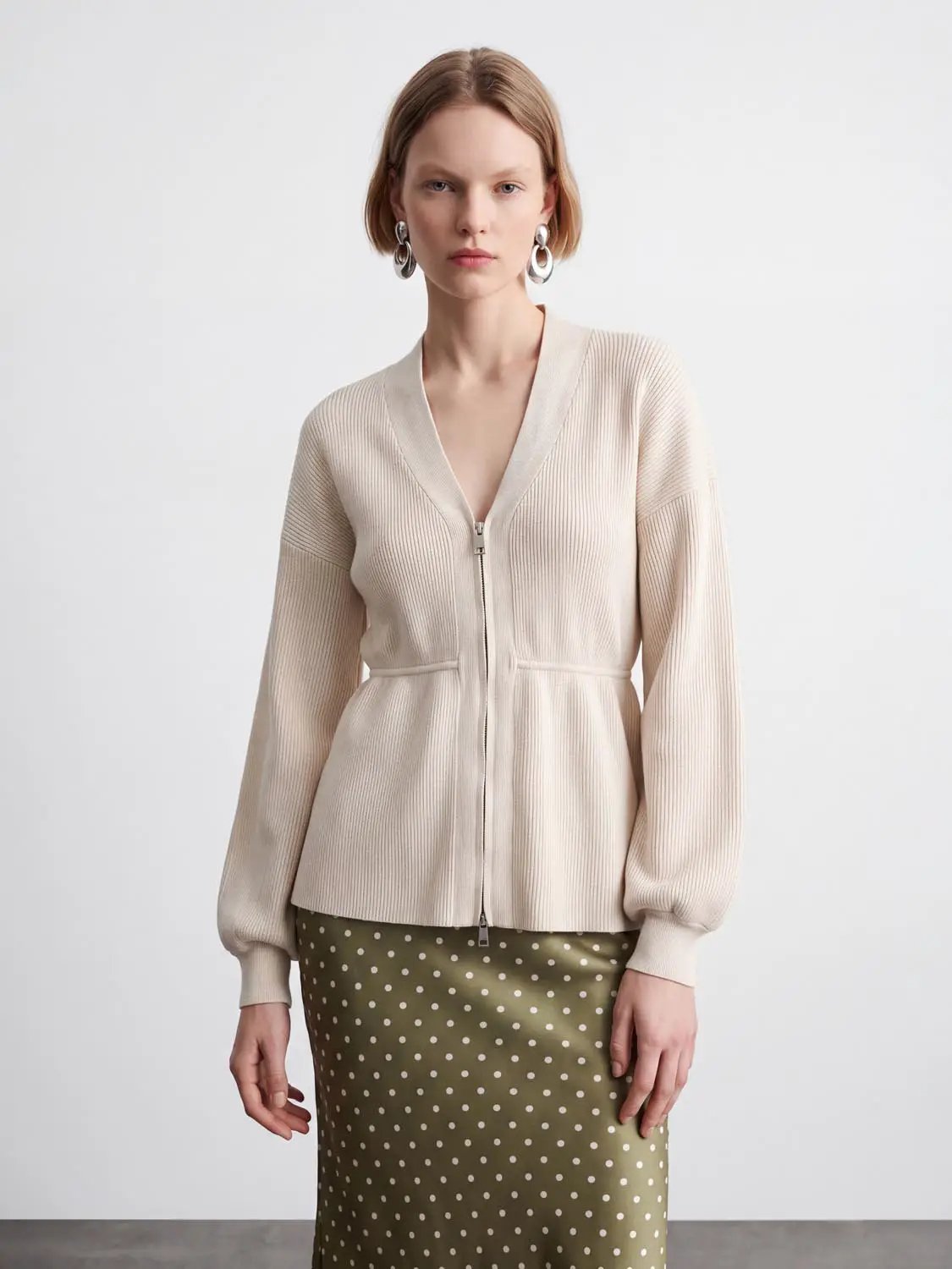 Zip Up Balloon Sleeve Knitted Cardigan in cream with ribbed knit and front zipper.
