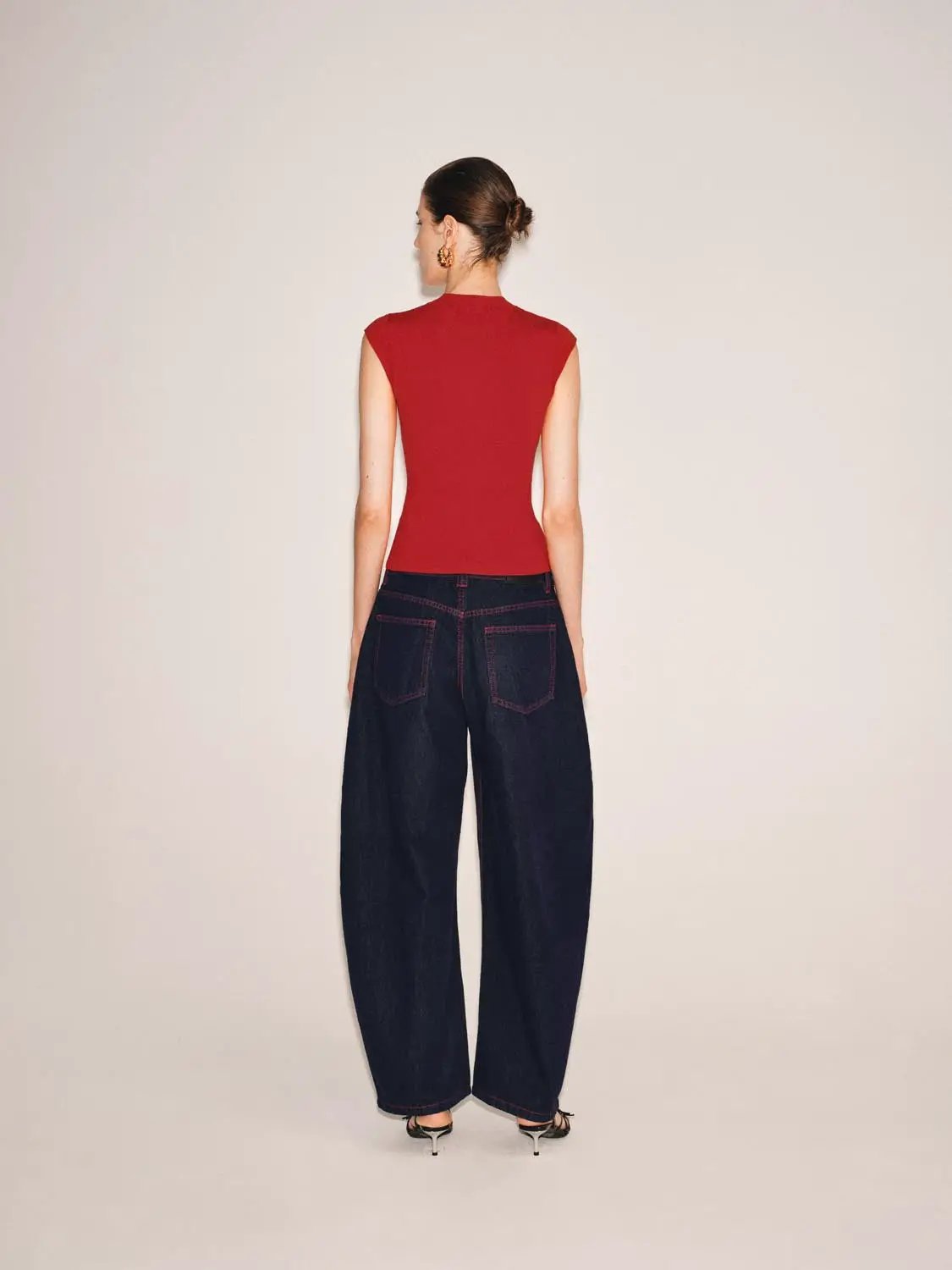 Knitted top in red, sleeveless fitted, back view with dark denim wide-leg jeans