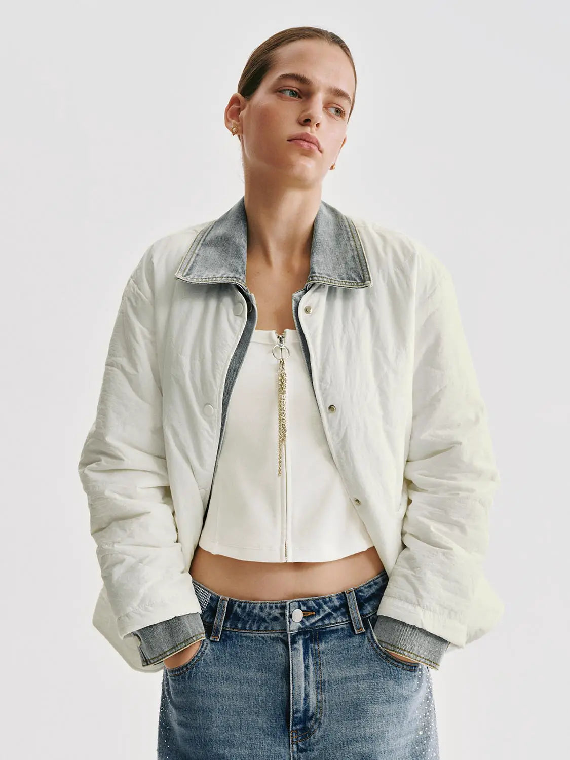 Padded jacket in cream with a denim contrast collar and cuffs, model wearing it over a white top and blue jeans.