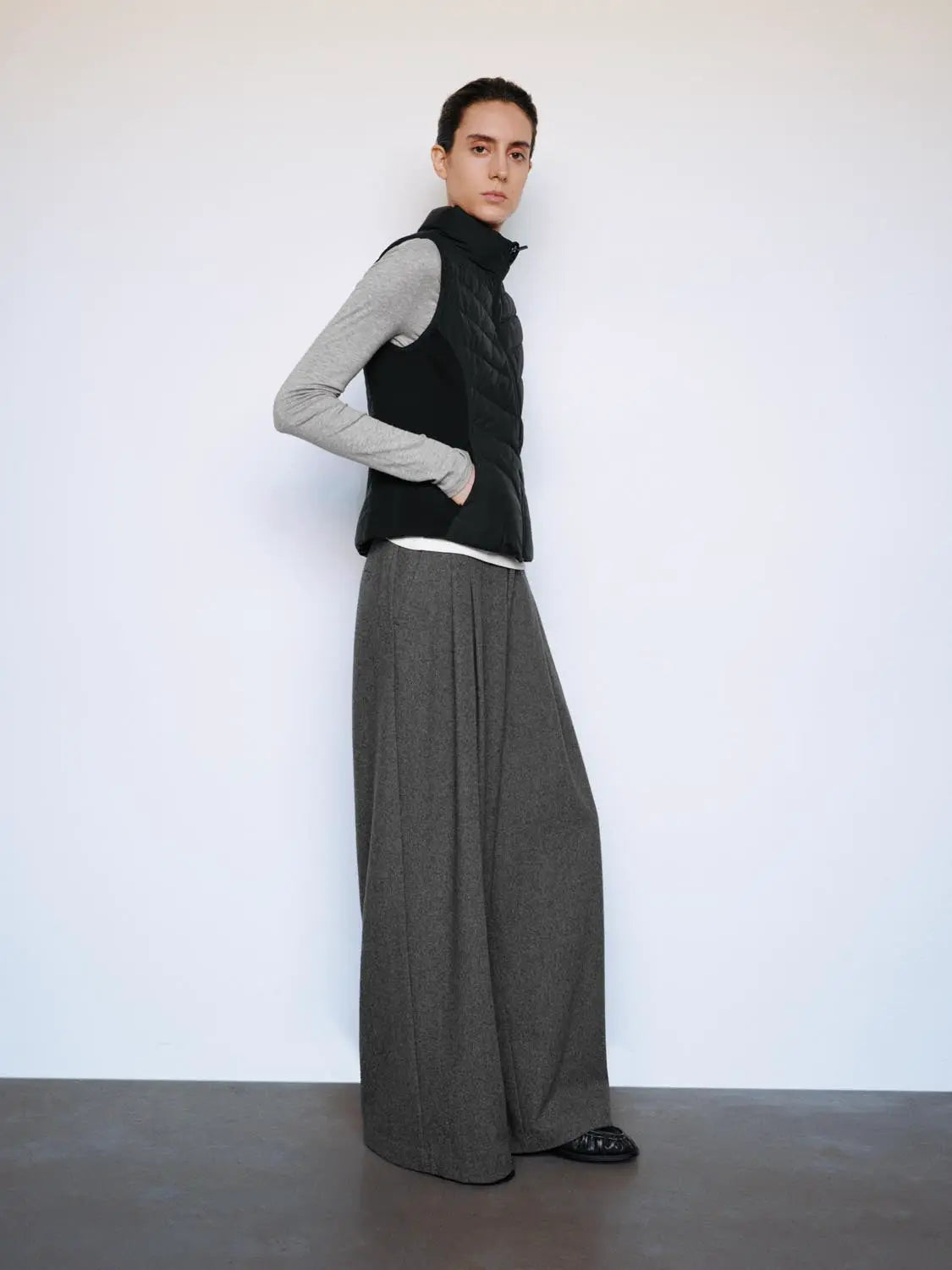 Down Jacket black quilted vest worn by model with grey long-sleeve top and wide-leg trousers