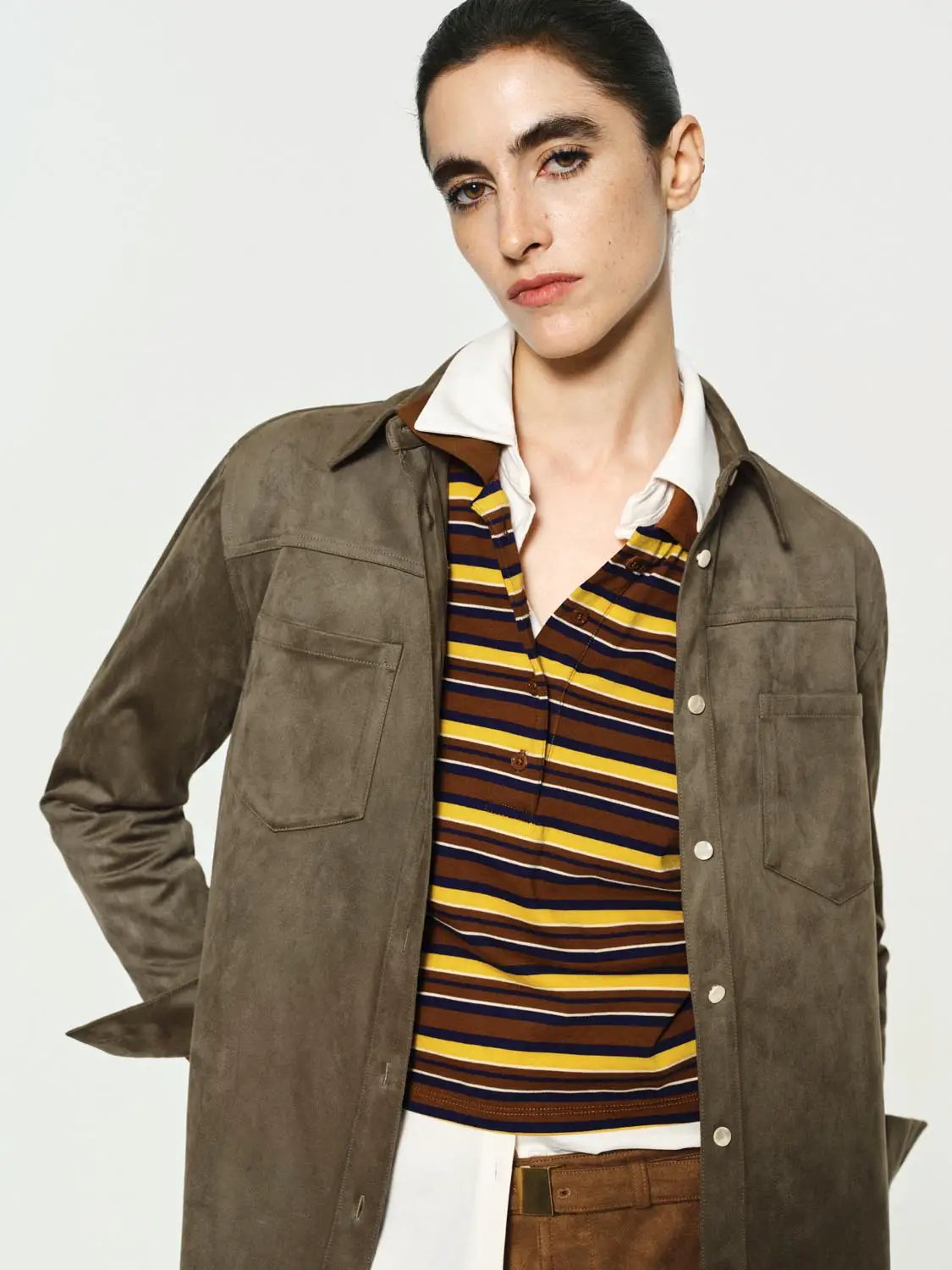 Button-down striped shirt in brown, yellow, and navy worn under a taupe suede jacket