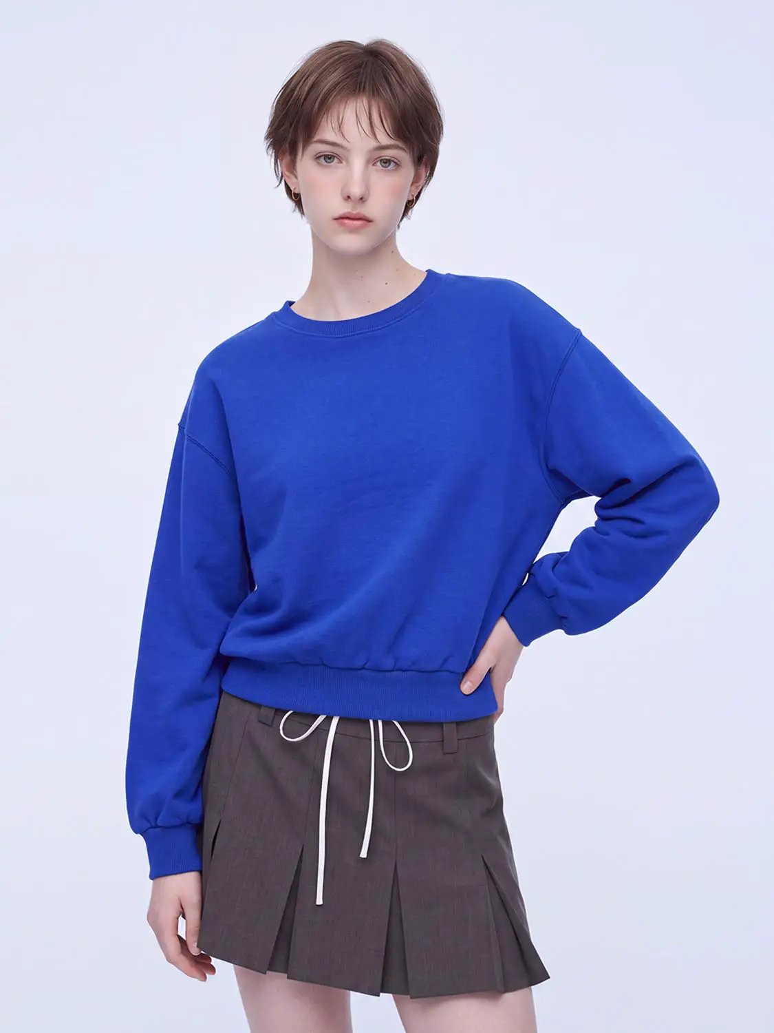 Sweatshirt, blue oversized with ribbed cuffs and hem; worn with brown pleated skirt