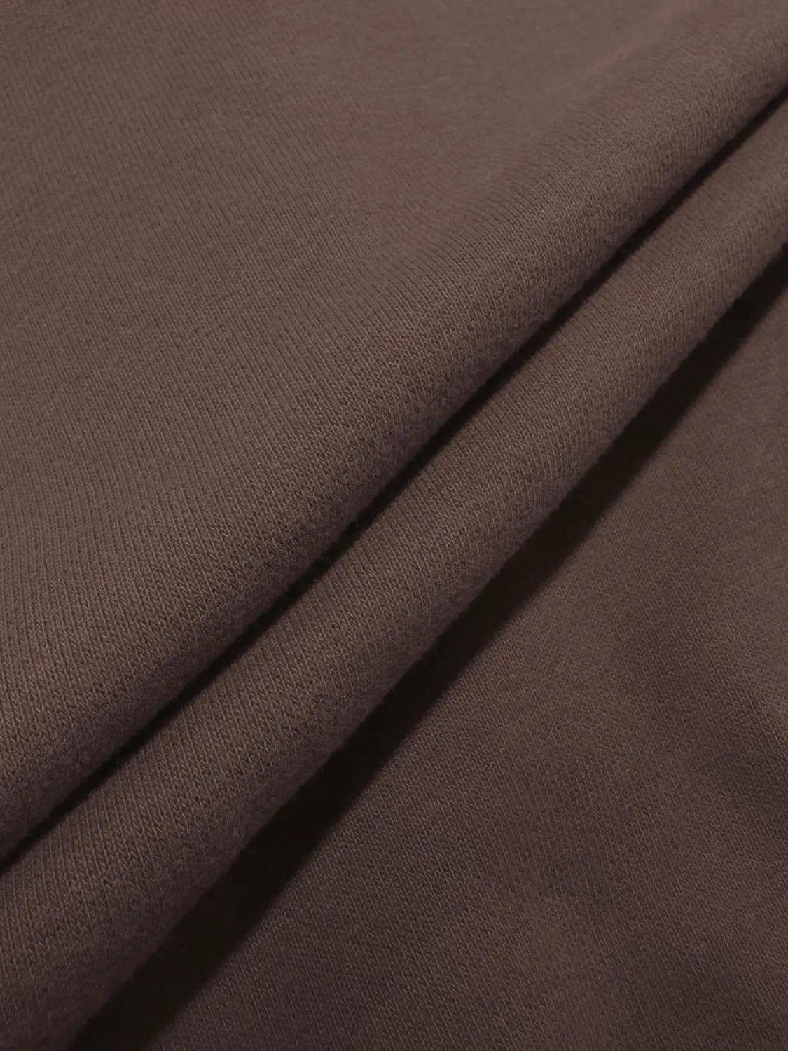 Sweatshirt fabric in brown close-up with knit texture and folded edges