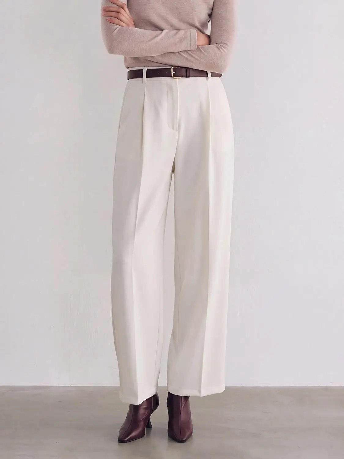 Wide-leg pants in cream with a brown belt, styled with a taupe top and brown ankle boots.