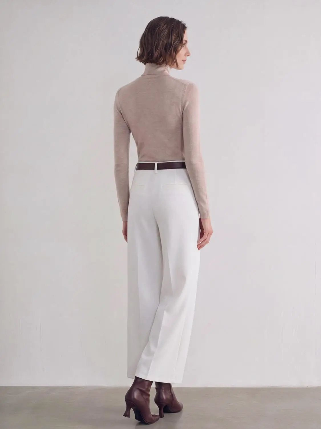 Wide-leg pants, white with brown belt, back view of model wearing beige top