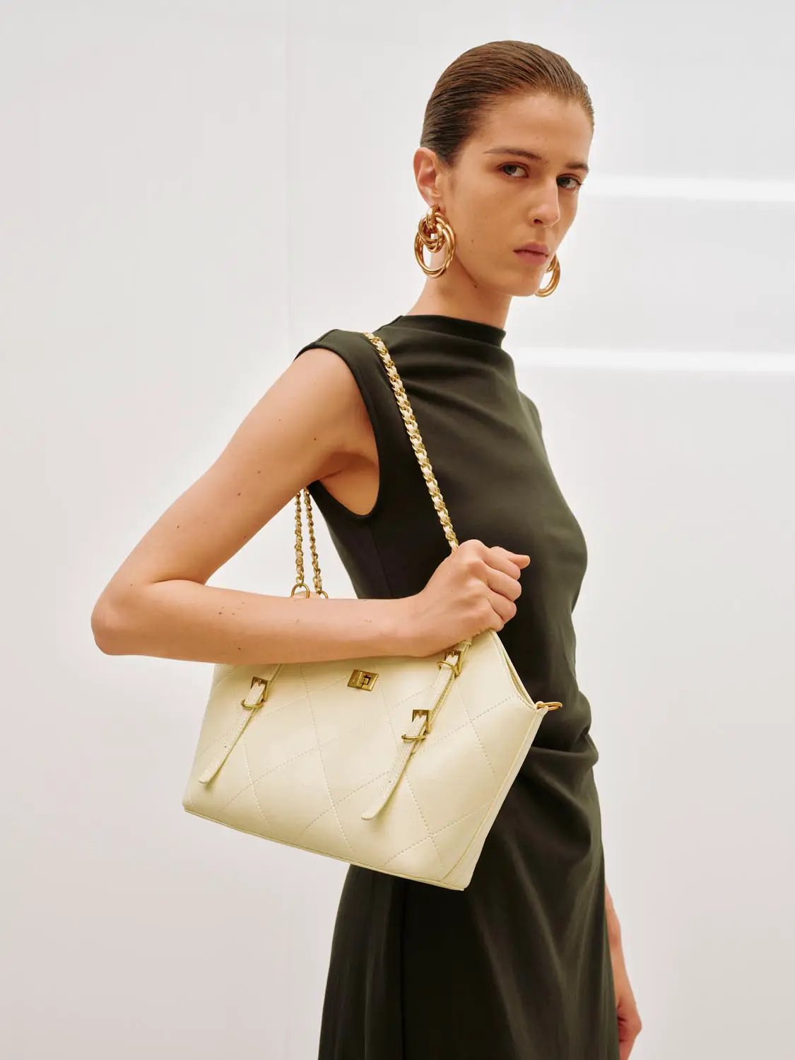 A-Line dress in olive-green, sleeveless; two-item set with a cream quilted handbag featuring a gold-tone chain.