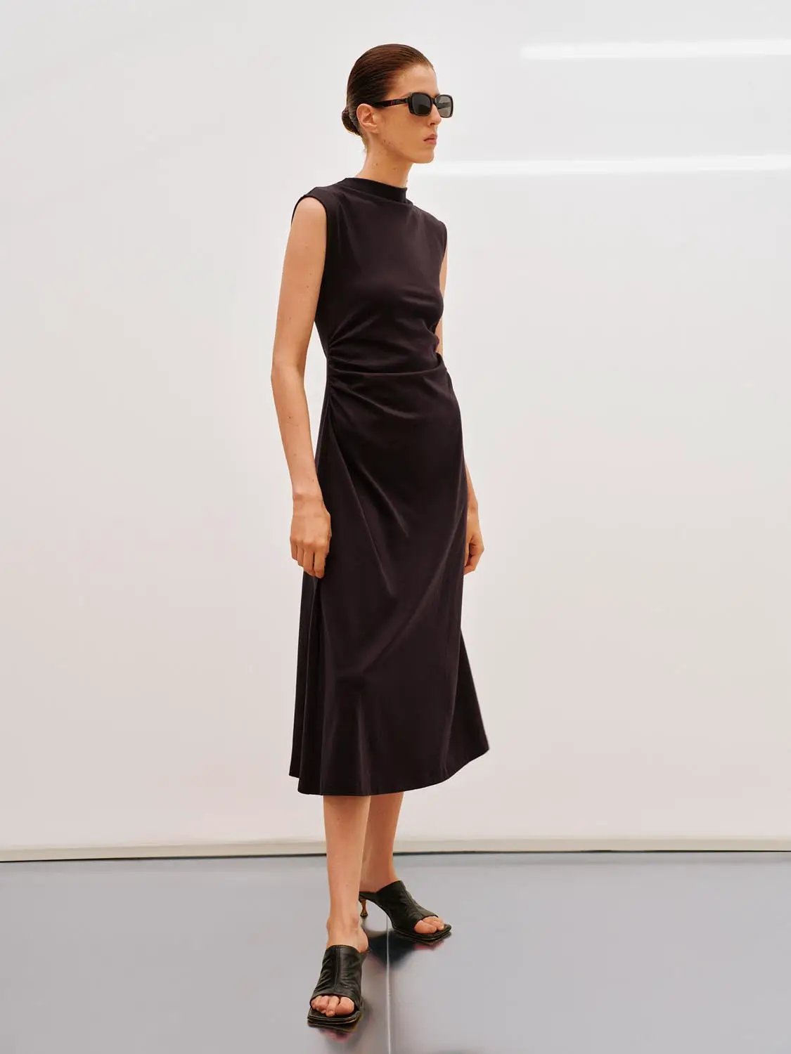 A-line dress in black, sleeveless with wrapped waist, midi length.