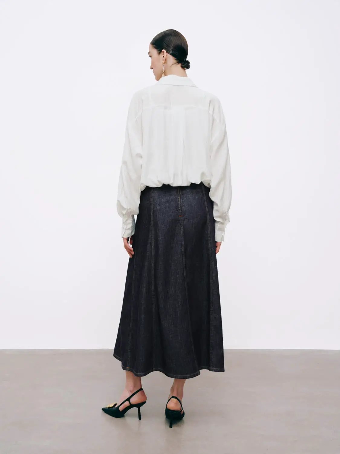 High-Waisted Stitch Detail Seamed Cotton Denim Midi Skirt in dark indigo, back view with white blouse.