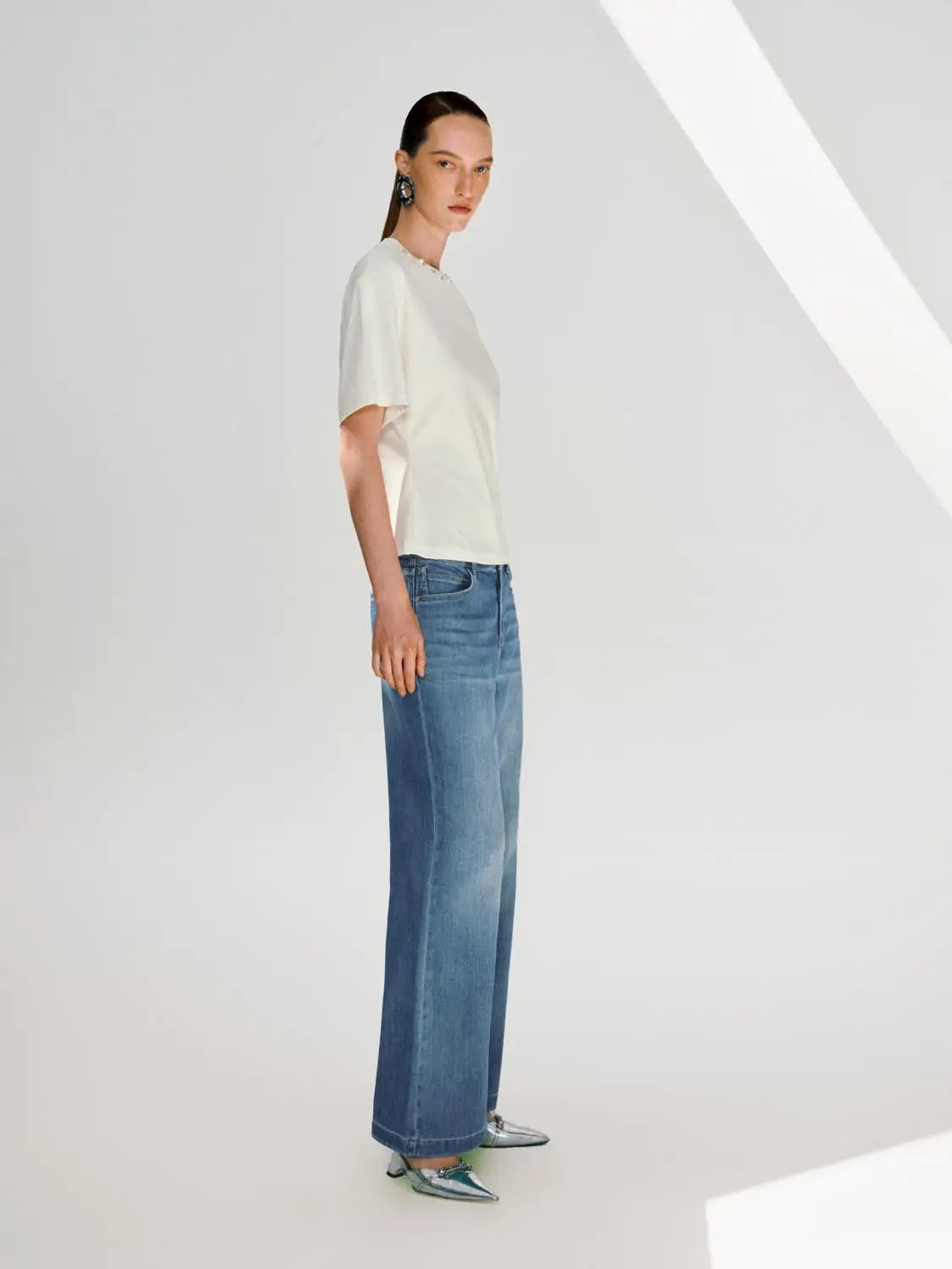 Wide-leg cotton-blend jeans with subtle wash worn by model in white top.