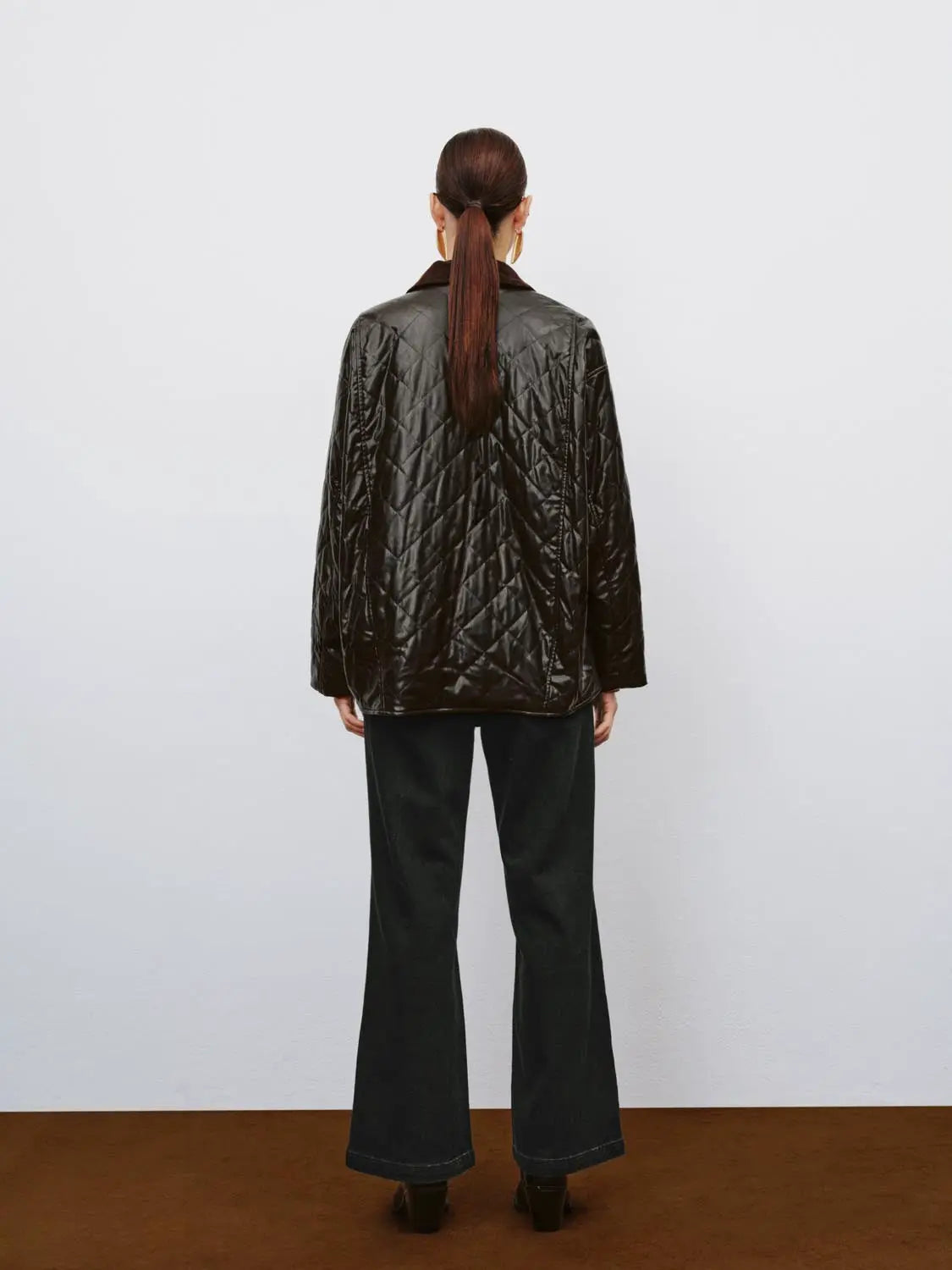 Jeans, black wide-leg denim, back view of model wearing a quilted black jacket.