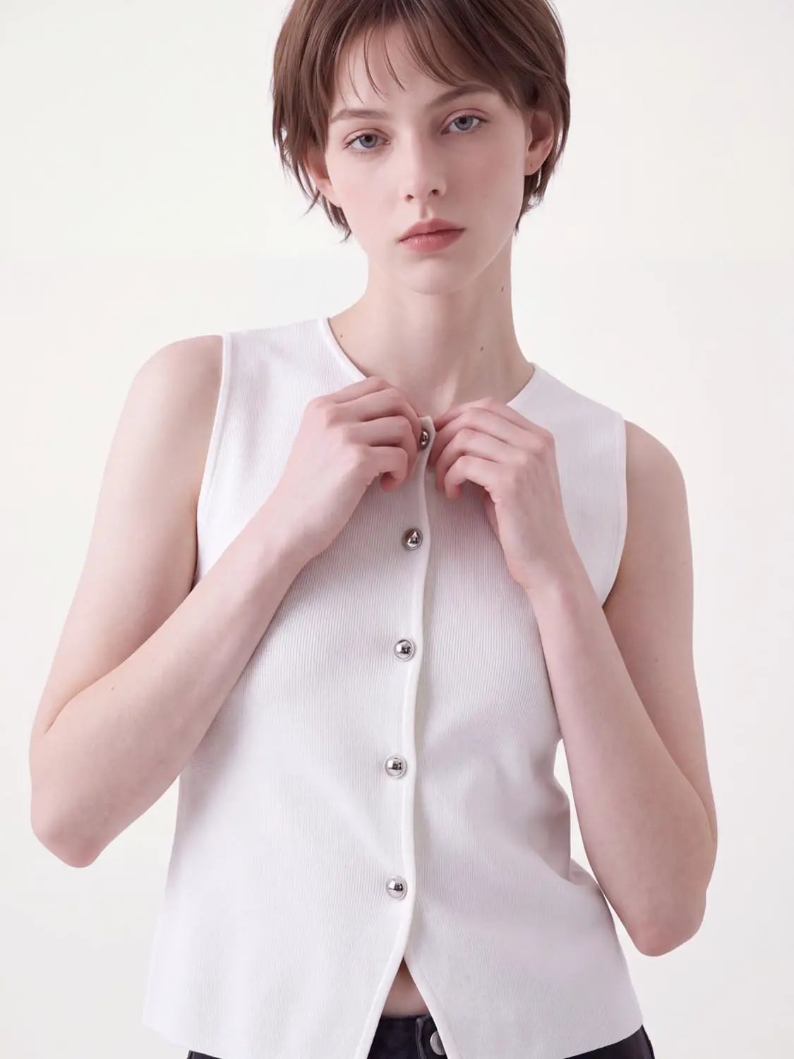 Round neck button-front sleeveless cropped knit vest in white.